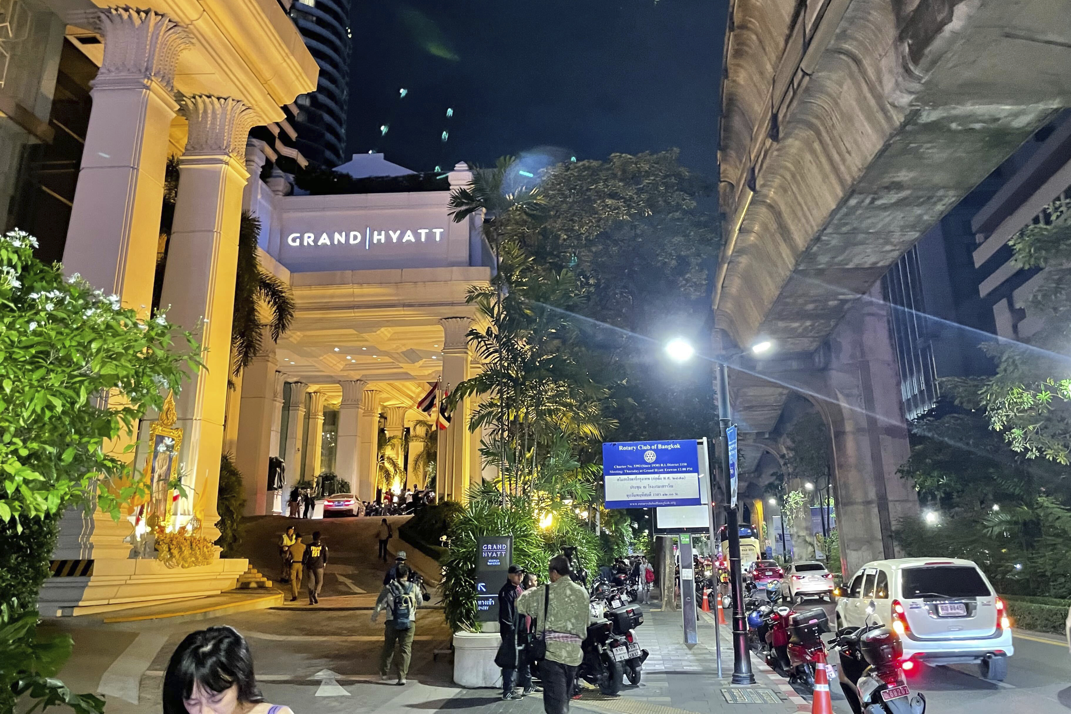 People walk outside a hotel where a number of people were found dead in Bangkok, Thailand, Tuesday, July 16, 2024. (AP Photo/Napat Kongsawad)