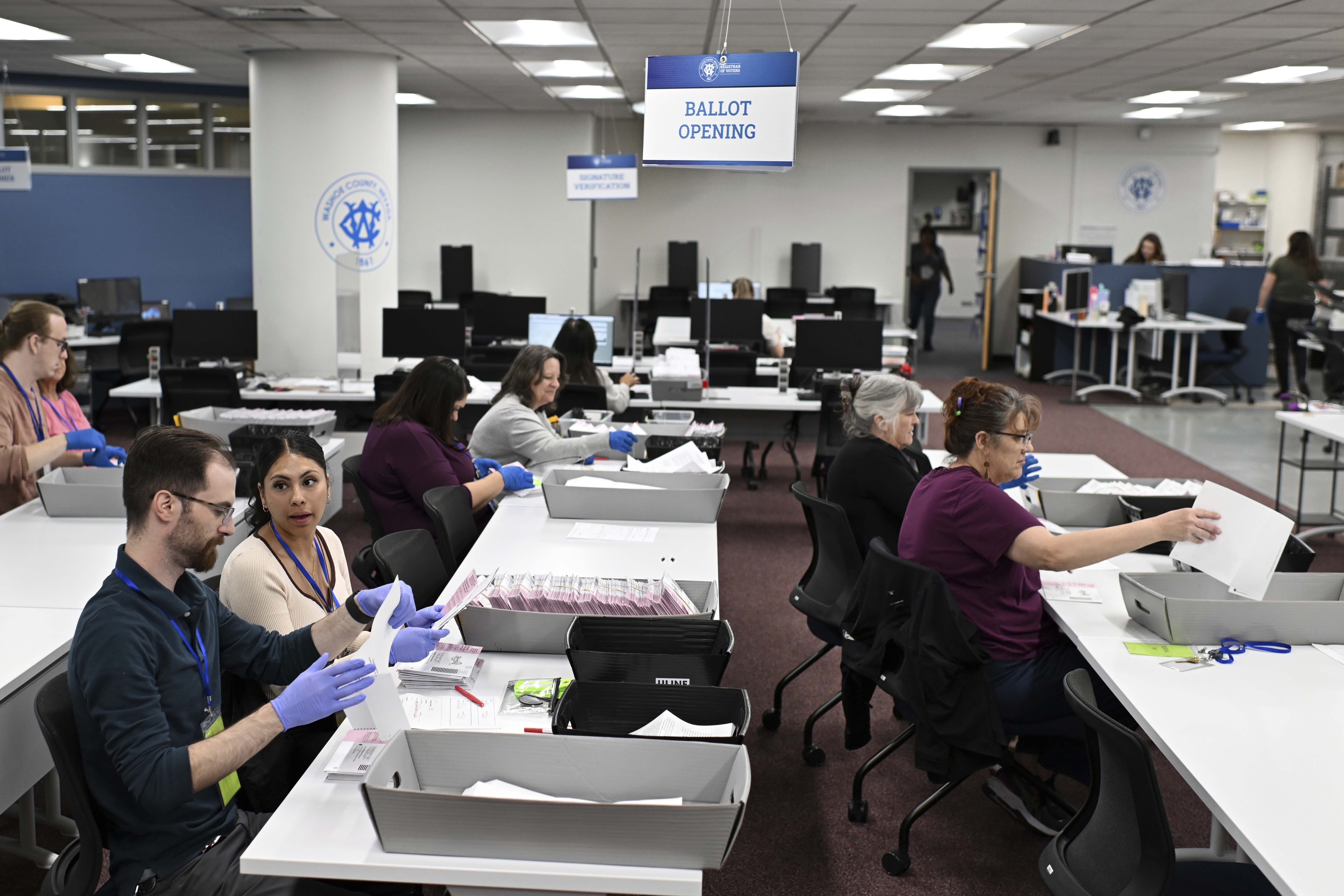 FILE - County employees open ballots in the ballot opening area of the mail ballot processing room at the Washoe County Registrar of Voters office in Reno, Nev., June 3, 2024. Commissioners in Nevada's second most populous county certified the results of two local recounts on Tuesday, July 16, reversing course on a controversial vote against certification that spurred legal action and put Washoe County in unchartered legal territory. (AP Photo/Andy Barron, File)