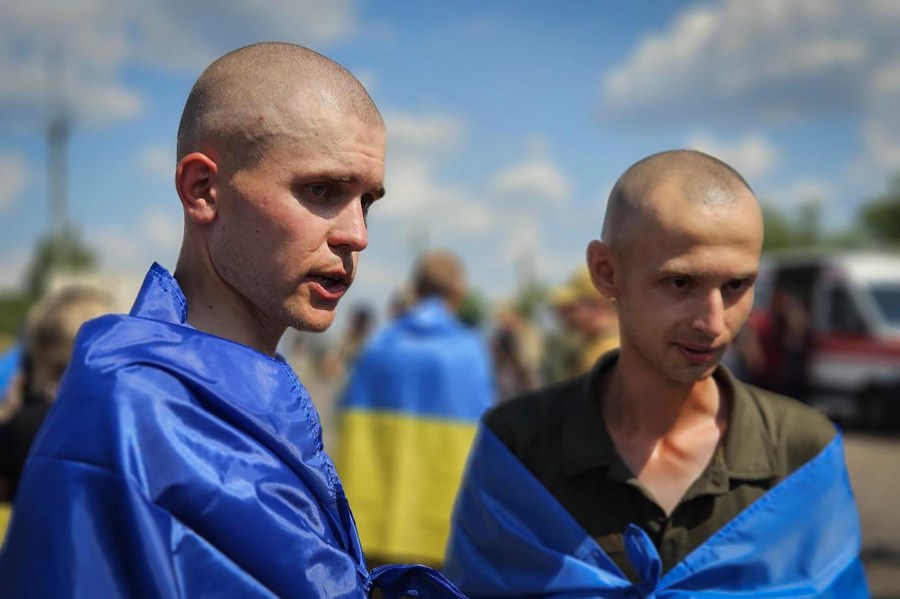 In this photo provided by the Ukrainian Presidential Press Office on Wednesday, July 17, 2024, Ukrainian prisoners of war wrapped in national flags pose for a photo after a prisoners exchange at an undisclosed location in Ukraine. (Ukrainian Presidential Press Office via AP)