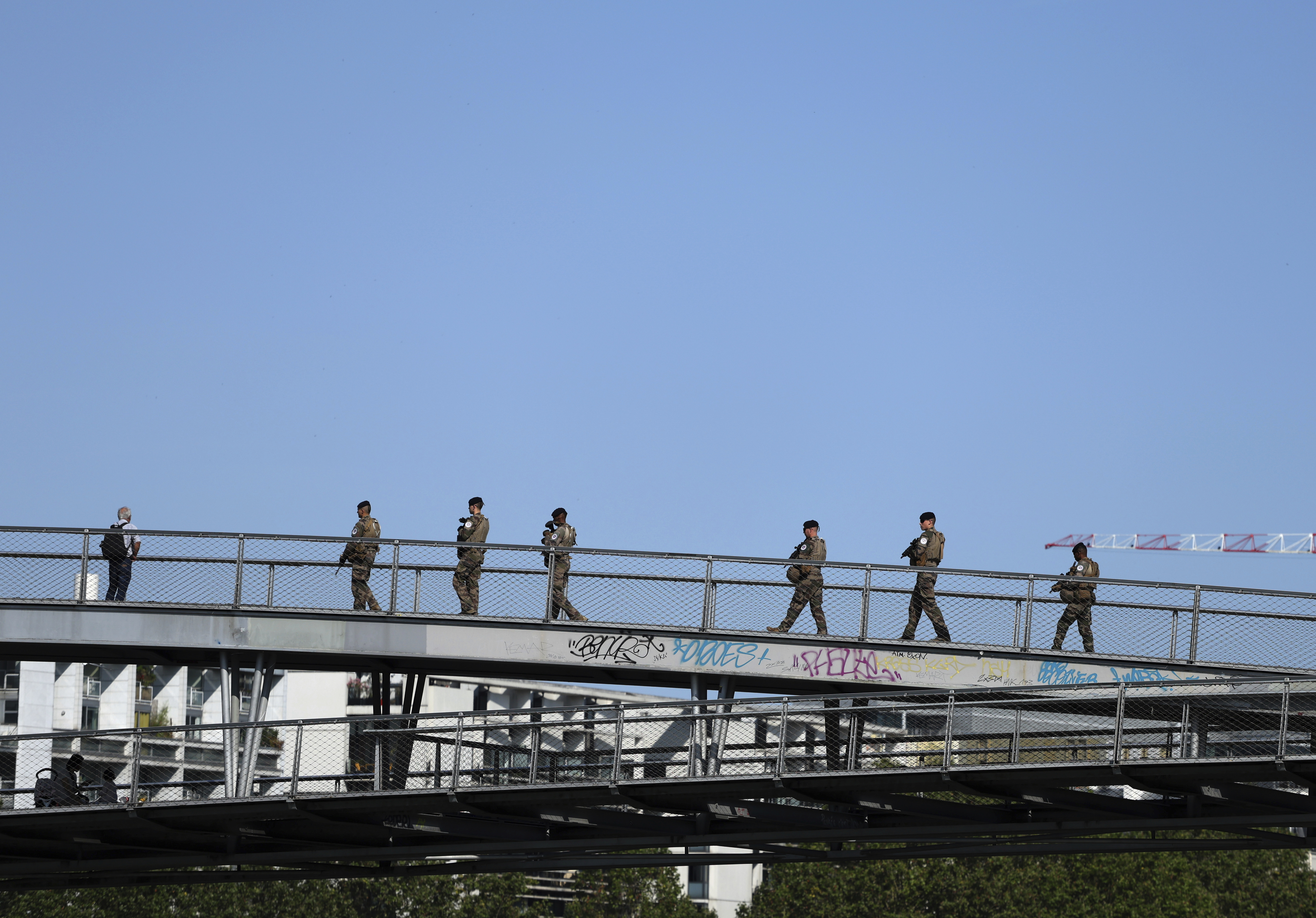 Soldiers patrol on a footbridge over the Seine river, Wednesday, July 17, 2024 in Paris. France's armed forces held a demonstration of the security measures planned on the River Seine, both in and out of the water, to make it safe for athletes and spectators during the opening ceremony of the Paris Olympics. Organizers have planned a parade of about 10,000 athletes through the heart of the French capital on boats on the Seine along a 6-kilometer (3.7-mile) route at sunset on July 26. (AP Photo/Aurelien Morissard)