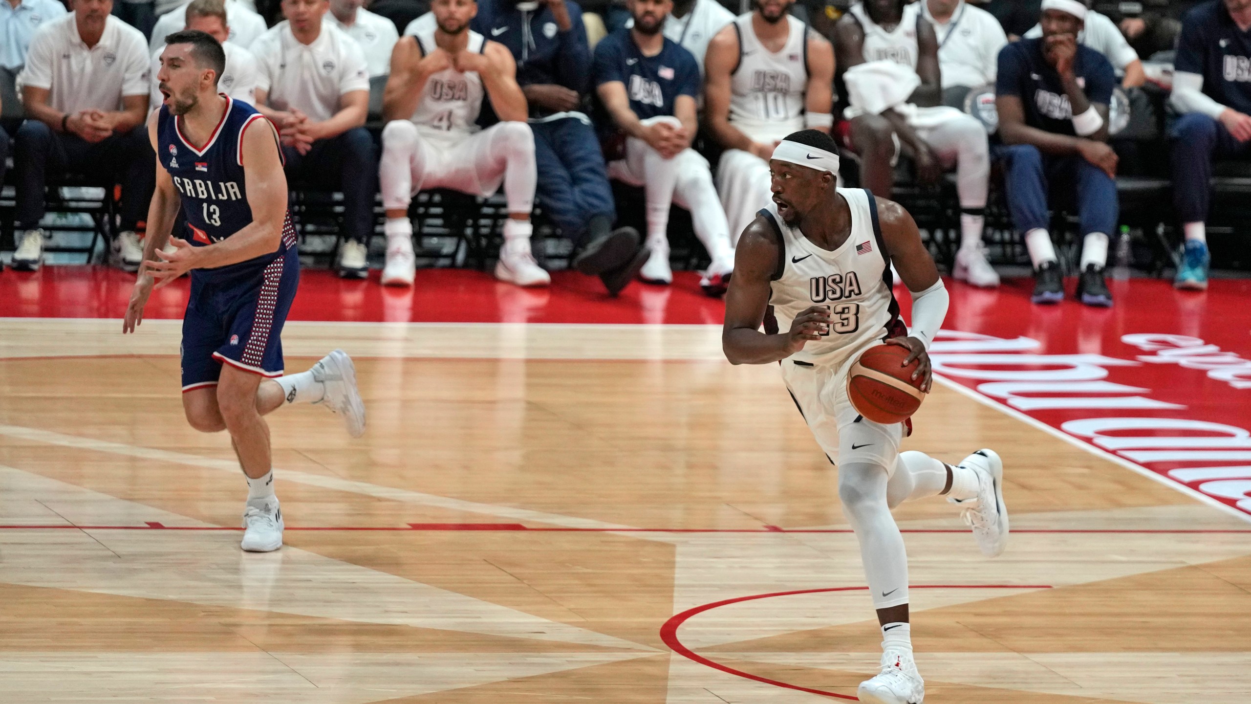 United States' Bam Adebayo, right, drives to the basket during an exhibition basketball match between Serbia and the United States at the USA Basketball Showcase, ahead of the 2024 Paris Olympic basketball tournament, in Abu Dhabi, United Arab Emirates, Wednesday, July 17, 2024. (AP Photo/Altaf Qadri)