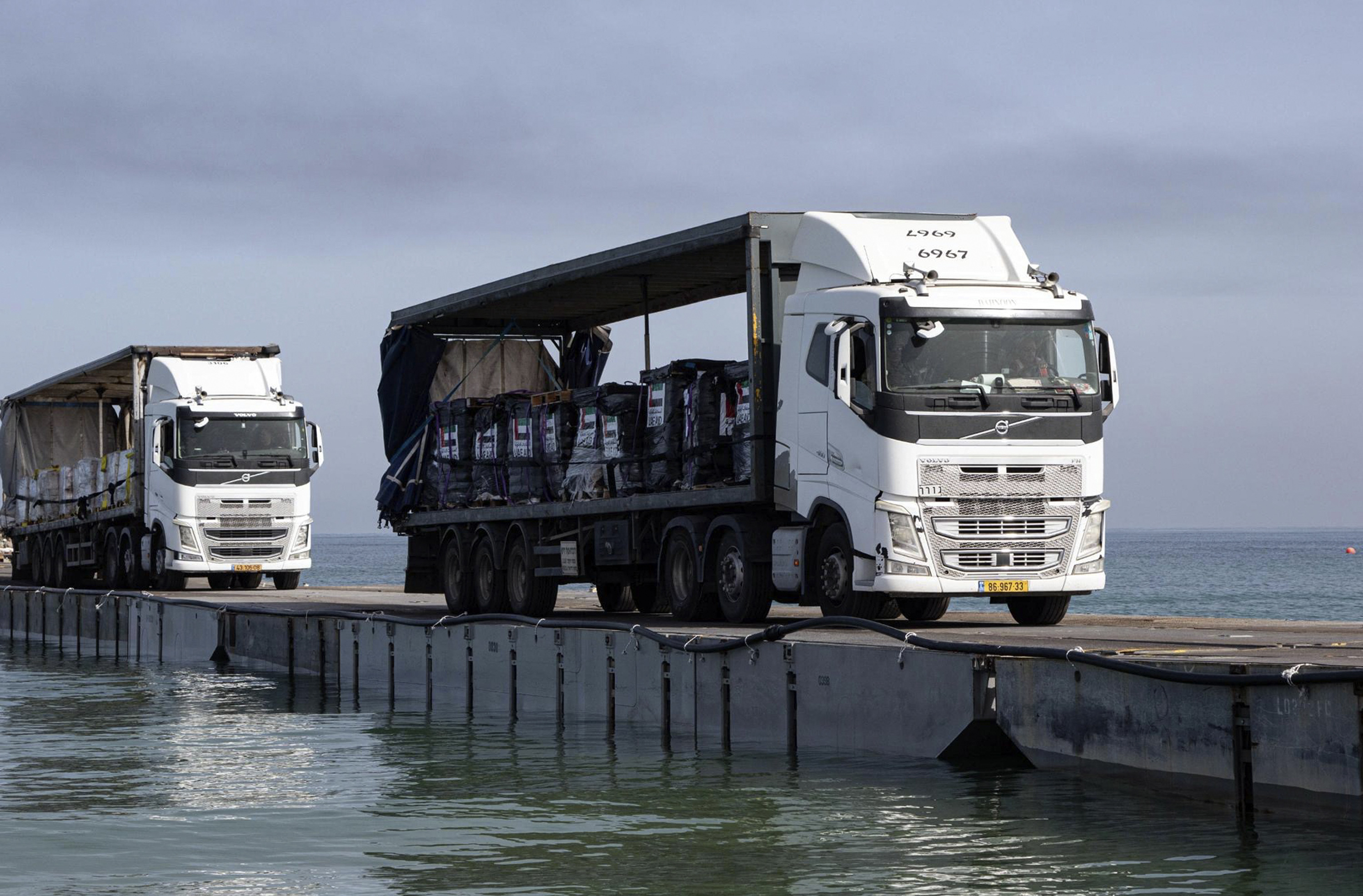 FILE - This image provided by the U.S. Army shows trucks loaded with humanitarian aid from the United Arab Emirates and the United States Agency for International Development cross the Trident Pier before arriving on the beach on the Gaza Strip, May 17, 2024. The U.S. military-built pier to carry humanitarian aid to Gaza is being dismantled and brought home, ending a mission that has been fraught with weather and security problems. (Staff Sgt. Malcolm Cohens-Ashley/U.S. Army via AP, File)