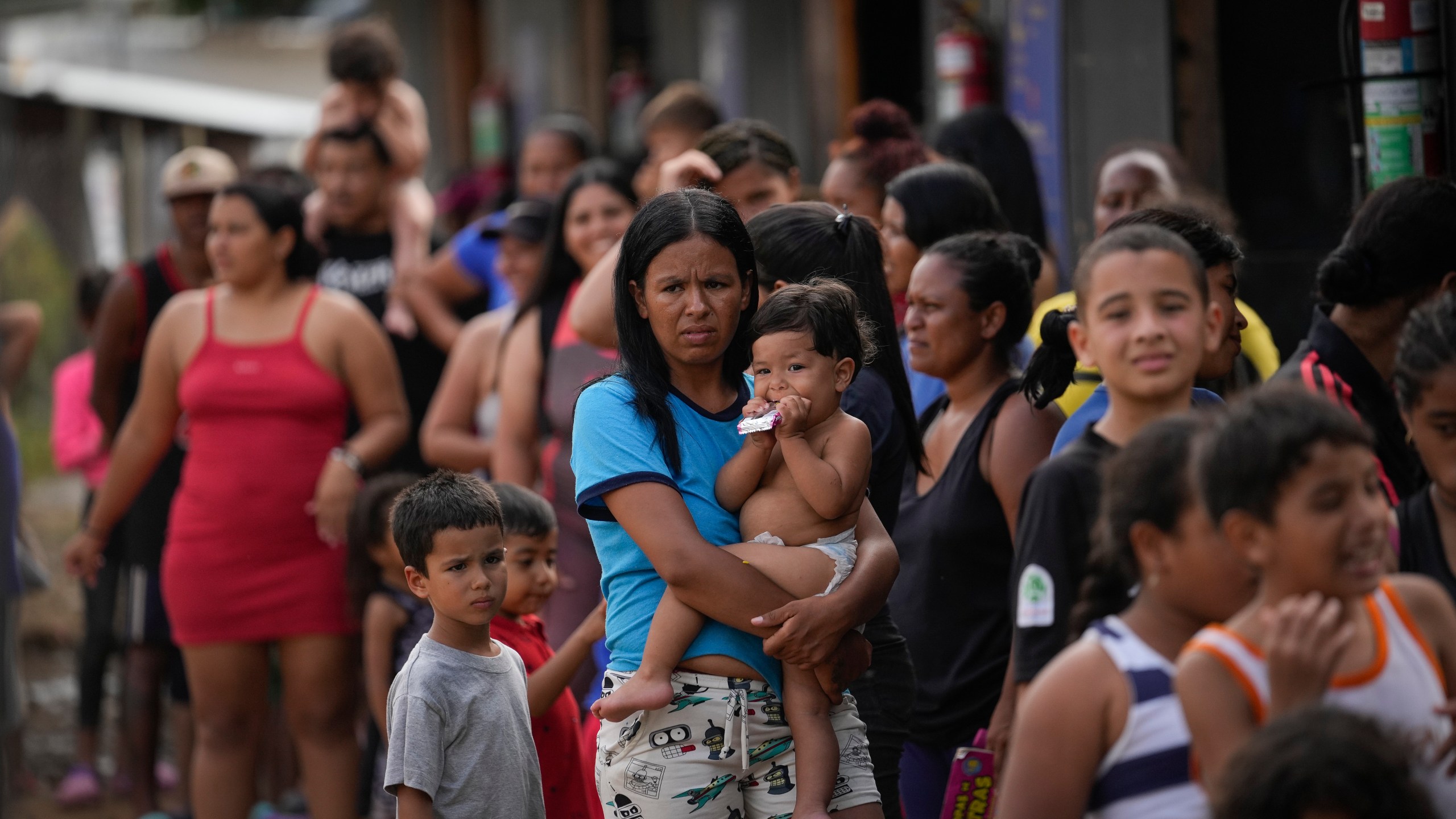 FILE - Venezuelan migrant Minorca Parra holds her daughter Karin Alvear as she lines up to receive food in a temporary camp after crossing the Darien Gap from Colombia in Lajas Blancas, Panama, June 27, 2024. Migration through the Darien Gap dividing Colombia and Panama has declined significantly this month since Panamanian President José Raúl Mulino took office and ordered authorities to get control of the dense jungle frontier, the country’s border police said Wednesday, July 17, 2024. (AP Photo/Matias Delacroix, File)