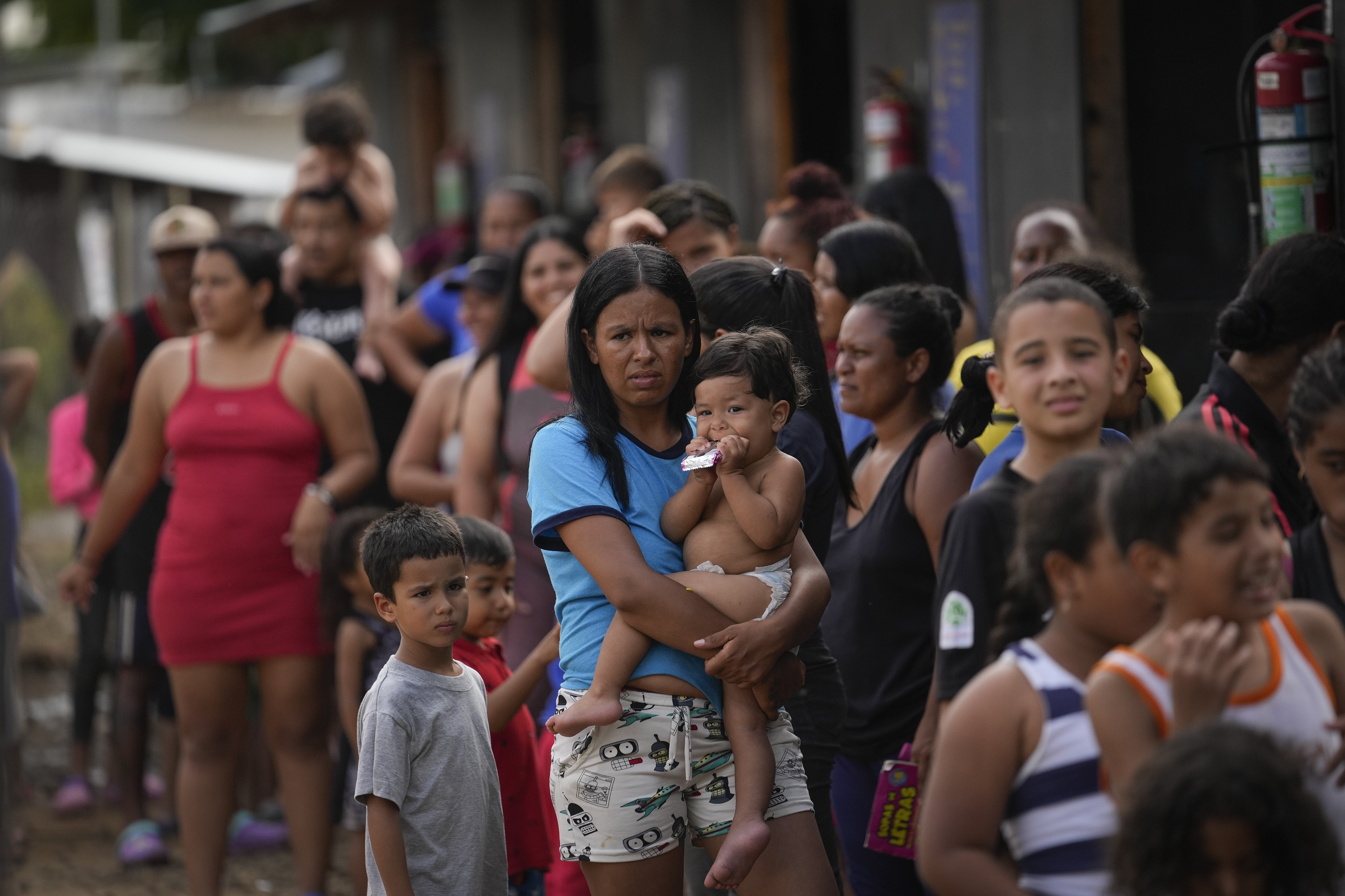 FILE - Venezuelan migrant Minorca Parra holds her daughter Karin Alvear as she lines up to receive food in a temporary camp after crossing the Darien Gap from Colombia in Lajas Blancas, Panama, June 27, 2024. Migration through the Darien Gap dividing Colombia and Panama has declined significantly this month since Panamanian President José Raúl Mulino took office and ordered authorities to get control of the dense jungle frontier, the country’s border police said Wednesday, July 17, 2024. (AP Photo/Matias Delacroix, File)