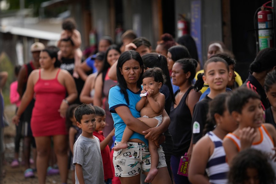 FILE - Venezuelan migrant Minorca Parra holds her daughter Karin Alvear as she lines up to receive food in a temporary camp after crossing the Darien Gap from Colombia in Lajas Blancas, Panama, June 27, 2024. Migration through the Darien Gap dividing Colombia and Panama has declined significantly this month since Panamanian President José Raúl Mulino took office and ordered authorities to get control of the dense jungle frontier, the country’s border police said Wednesday, July 17, 2024. (AP Photo/Matias Delacroix, File)