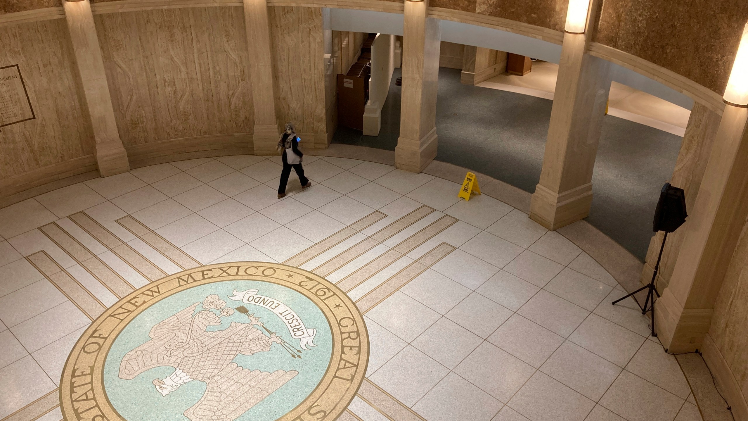 FILE - A pedestrian traverses the rotunda inside the New Mexico Capitol, March 16, 2023, in Santa Fe, N.M. Gov. Michelle Lujan Grisham is urging the Democratic-led Legislature to consider longer minimum sentences for gun-toting felons, restrictions on panhandling and an expansion of involuntary detention and treatment for mental health problems and addiction. (AP Photo/Morgan Lee, File)