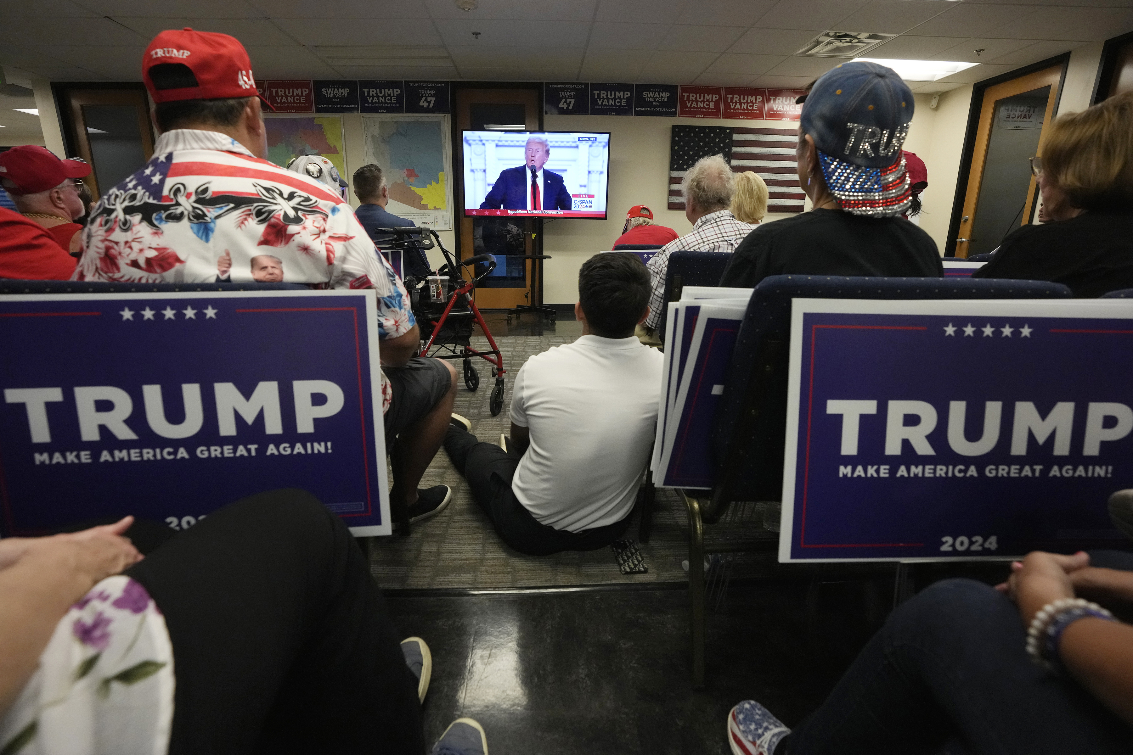 Supporters of Republican presidential candidate former President Donald Trump watch his speech at the Republican National Convention on a television from the Arizona GOP headquarters Thursday, July 18, 2024, in Phoenix. (AP Photo/Ross D. Franklin)