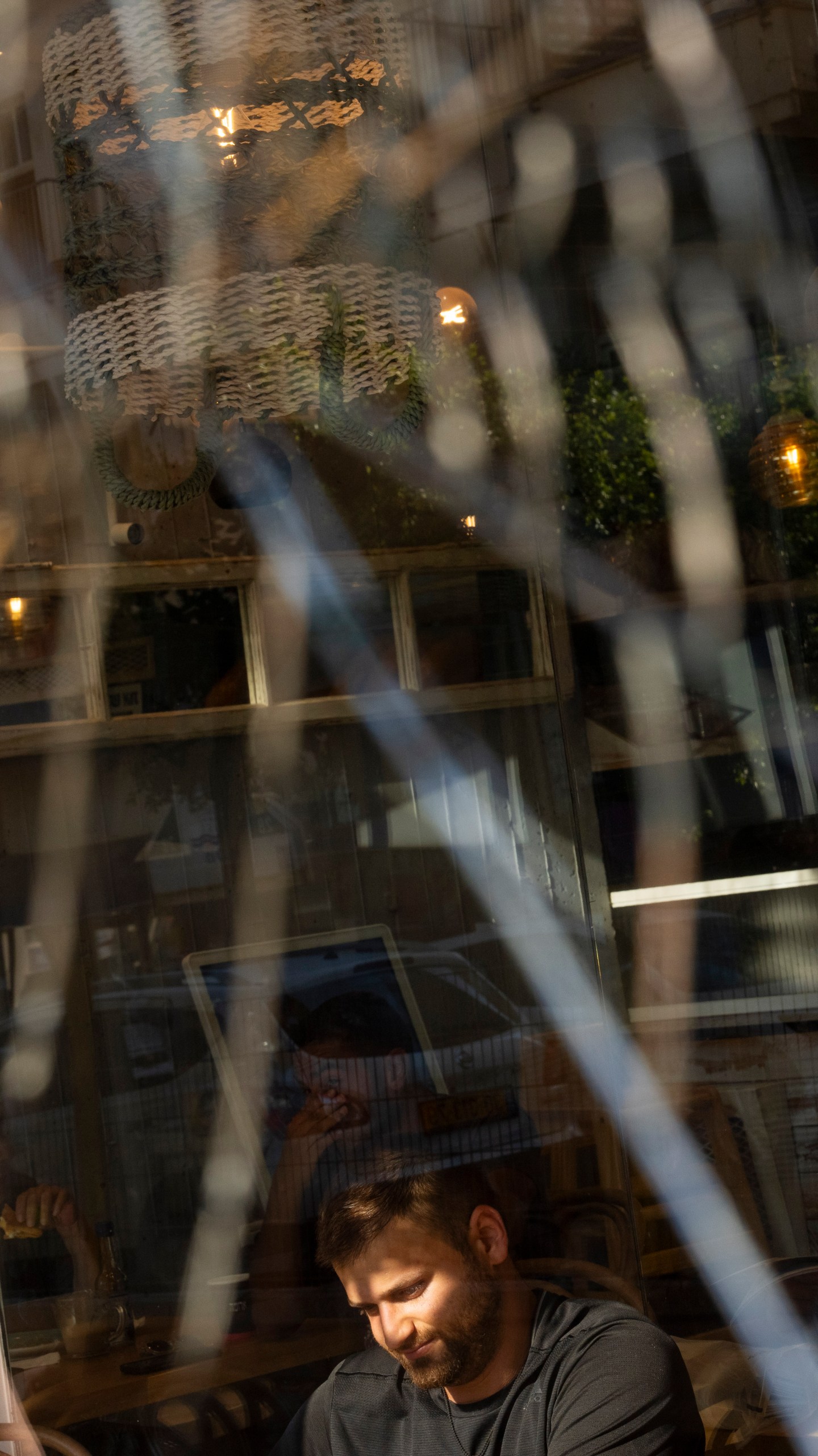 People are seen through a broken coffee shop window next to the scene of an explosive drone attack in Tel Aviv, Israel, Friday, July 19, 2024. Yemen's Houthi rebels claimed responsibility for a drone believed to have exploded above Tel Aviv early Friday morning. (AP Photo/Oded Balilty)