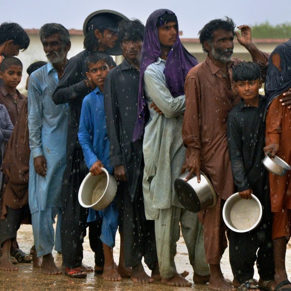 FILE - People wait in the rain to receive free food distributed from volunteers outside a camp for people displaced from coastal areas in Sujawal, Pakistan's southern district in the Sindh province, June 15, 2023, as Cyclone Biparjoy was approaching. (AP Photo/Pervez Masih, File)