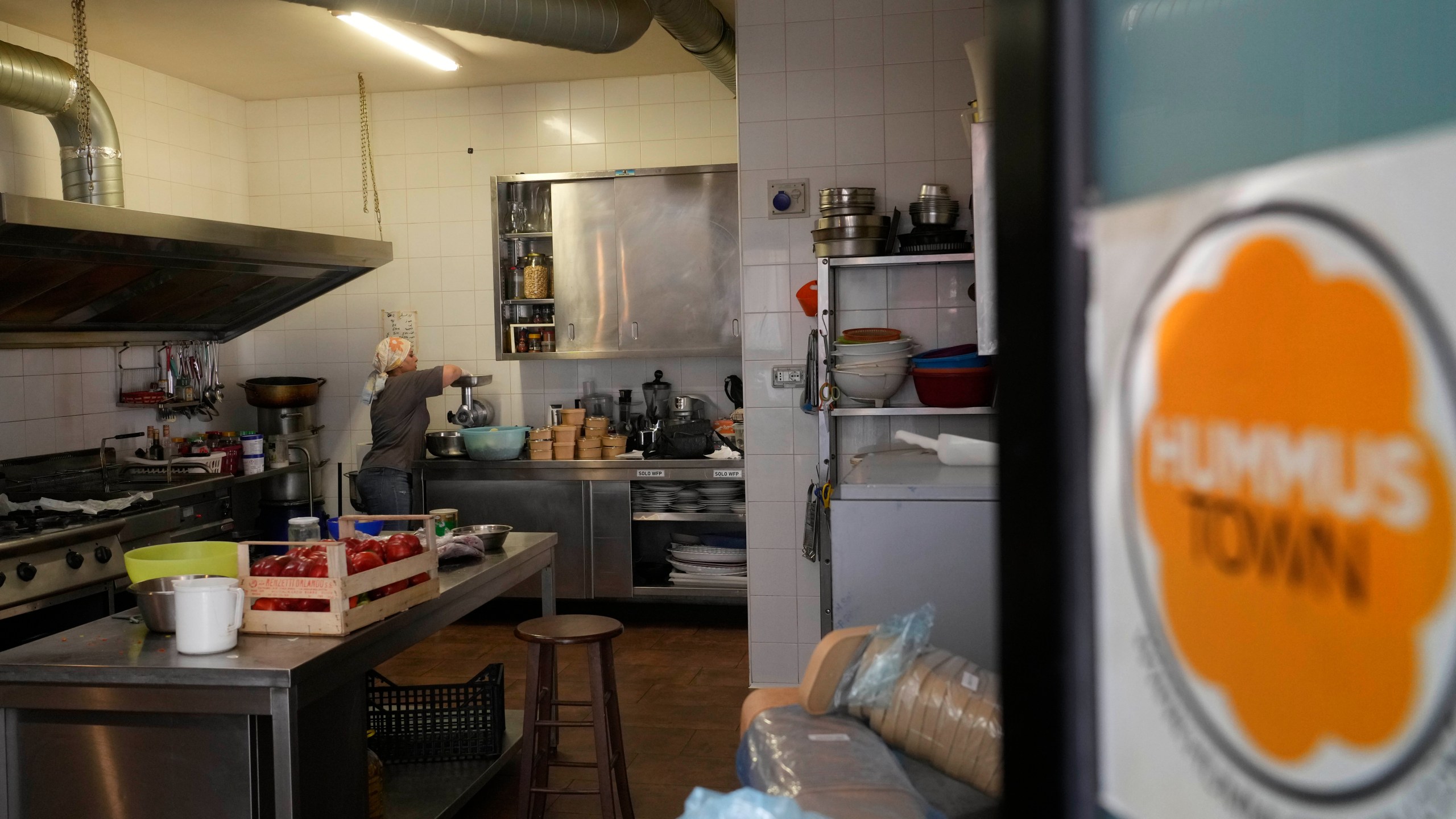 Ruqaia Agha, a Palestinian woman from Ramla, works in the HummusTown kitchen in Rome, Saturday, July 27, 2024. A pair of Syrians have created community that provides support to migrants and vulnerable people in Rome, by sharing the flavors of a homeland torn by civil war. Created in 2018 as a "humanitarian catering service," HummusTown originally aimed at raising funds for families and friends in Syria. (AP Photo/Gregorio Borgia)