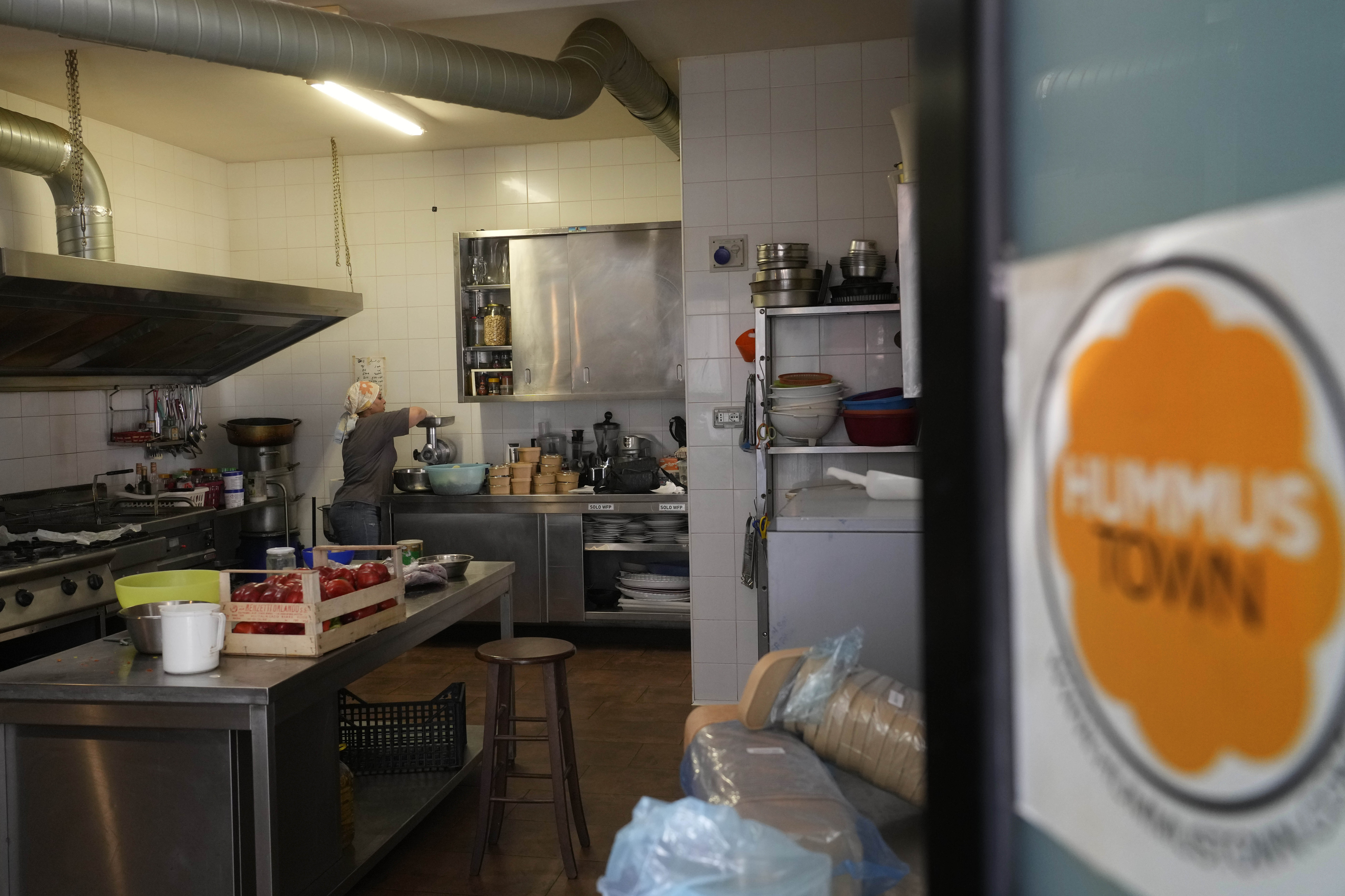 Ruqaia Agha, a Palestinian woman from Ramla, works in the HummusTown kitchen in Rome, Saturday, July 27, 2024. A pair of Syrians have created community that provides support to migrants and vulnerable people in Rome, by sharing the flavors of a homeland torn by civil war. Created in 2018 as a "humanitarian catering service," HummusTown originally aimed at raising funds for families and friends in Syria. (AP Photo/Gregorio Borgia)