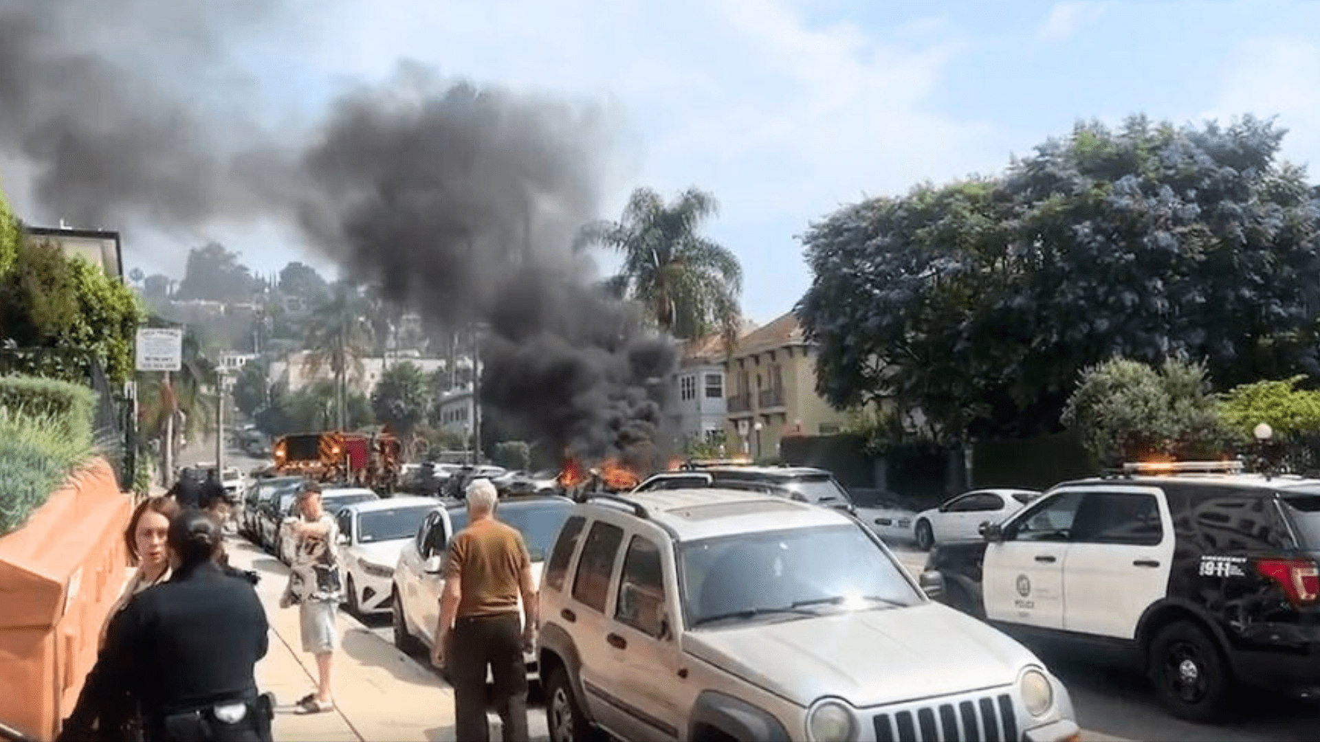 Bystanders look on as a vehicle was engulfed in flames in the Hollywood Hills on July 13, 2024. (Citizen)