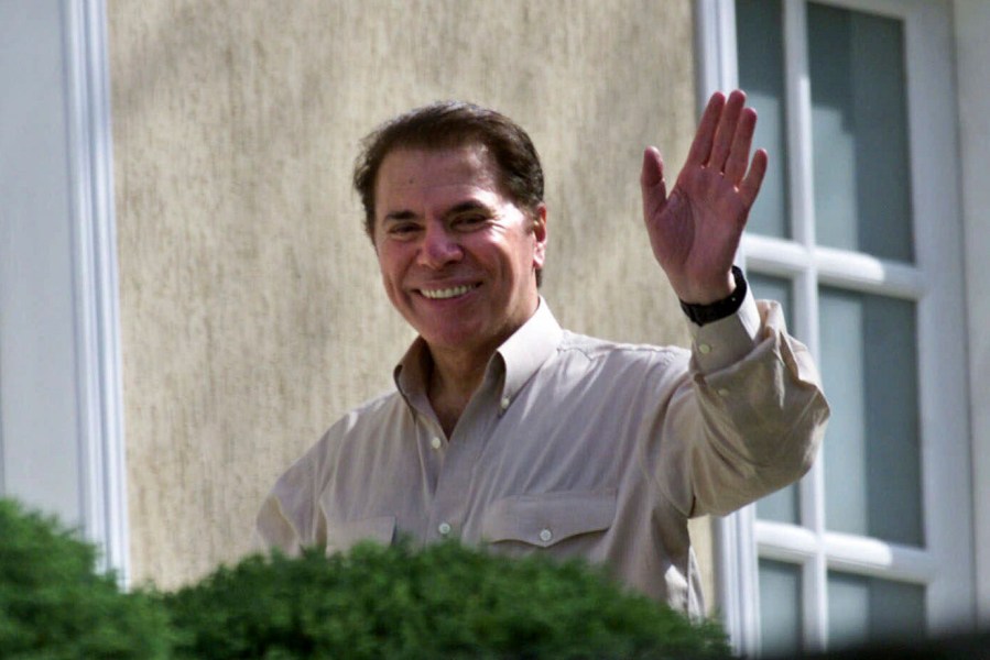 FILE - Brazilian TV mogul Silvio Santos waves from outside his home in Sao Paulo, Brazil on Thursday Aug. 30, 2001. (AP Photo/Dario Lopez-Mills)