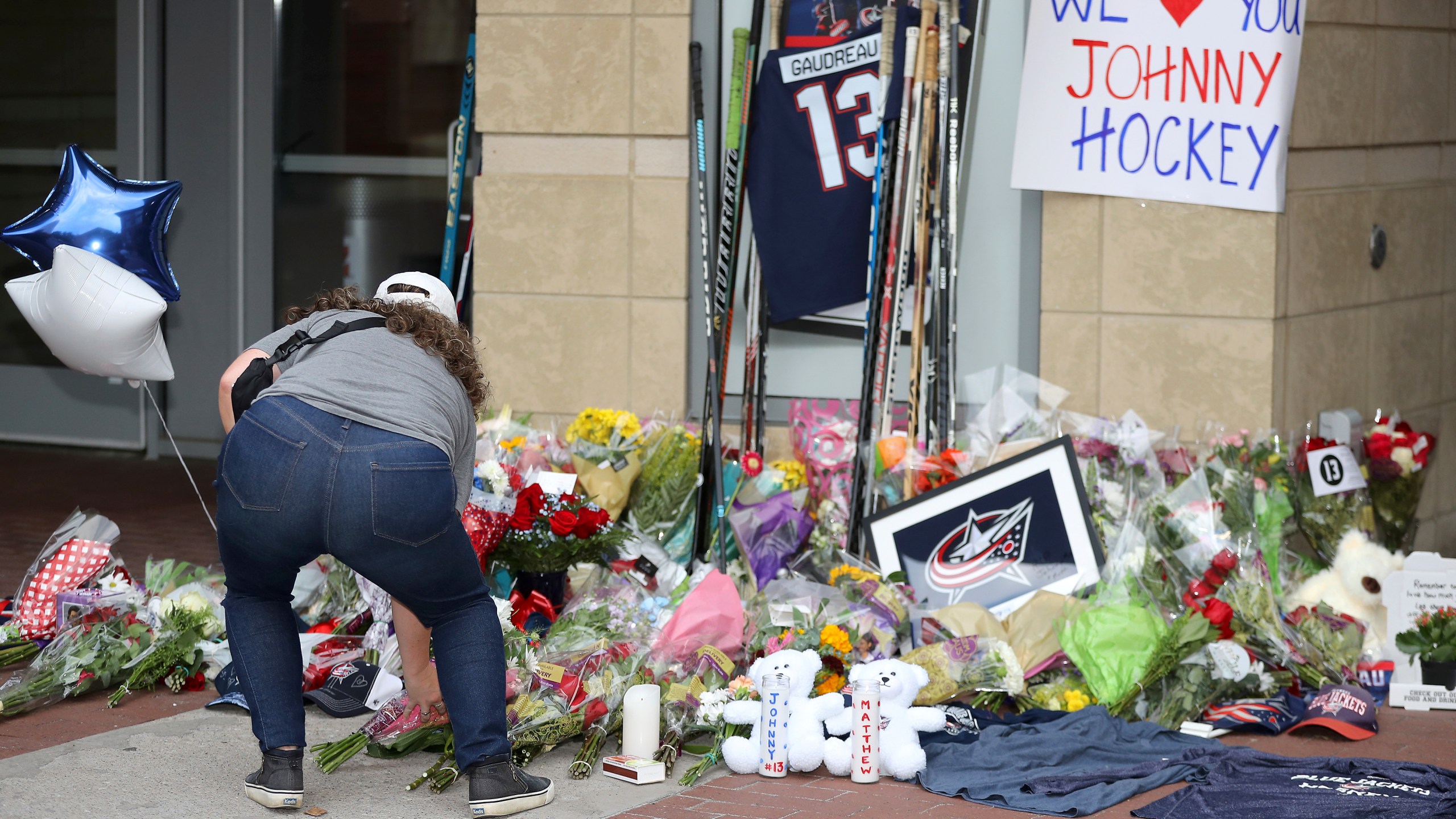 Kaitlin O'Hara of Columbus, places flowers at a memorial set up by fans for Blue Jackets hockey player Johnny Gaudreau in Columbus, Ohio, Aug. 30, 2024. Gaudreau, along with his brother Matthew, was fatally struck by a motorist while riding his bicycle on Thursday. (AP Photo/Joe Maiorana)