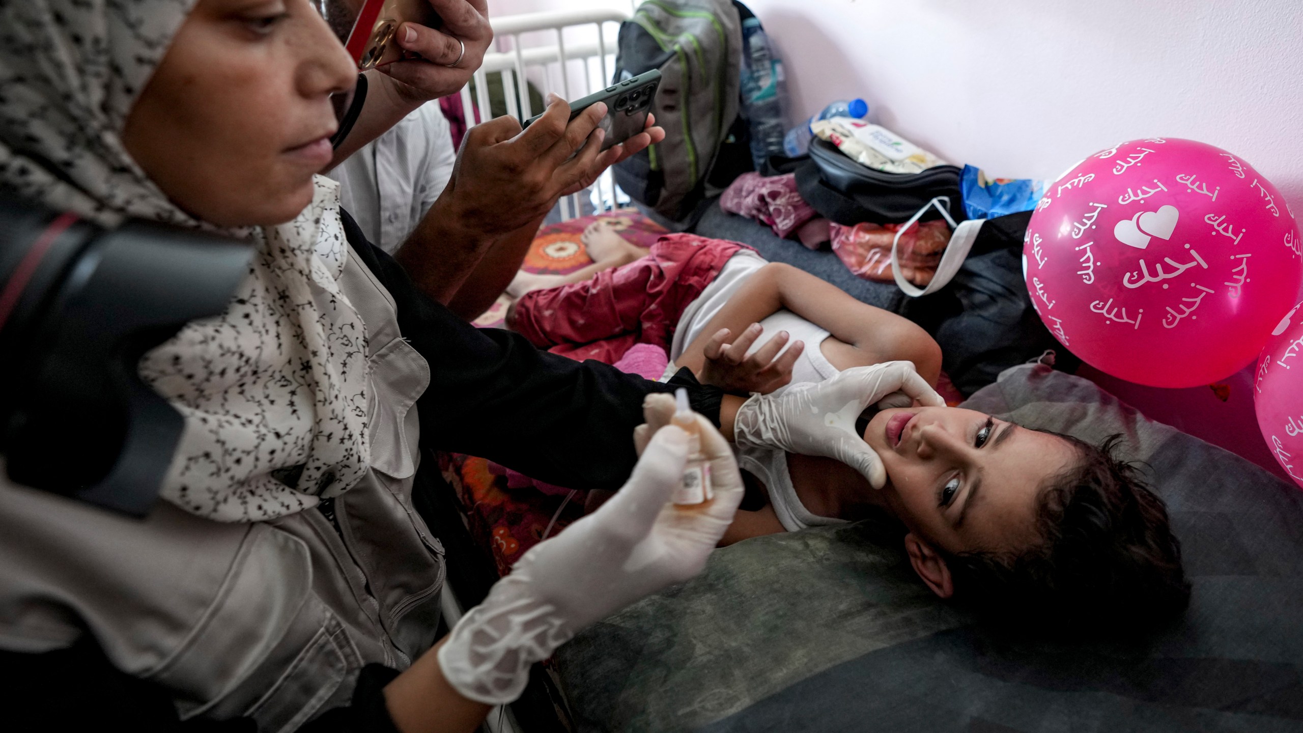 A health worker administers a polio vaccine to a child at a hospital in Khan Younis, Saturday, Aug. 31, 2024. (AP Photo/Abdel Kareem Hana)