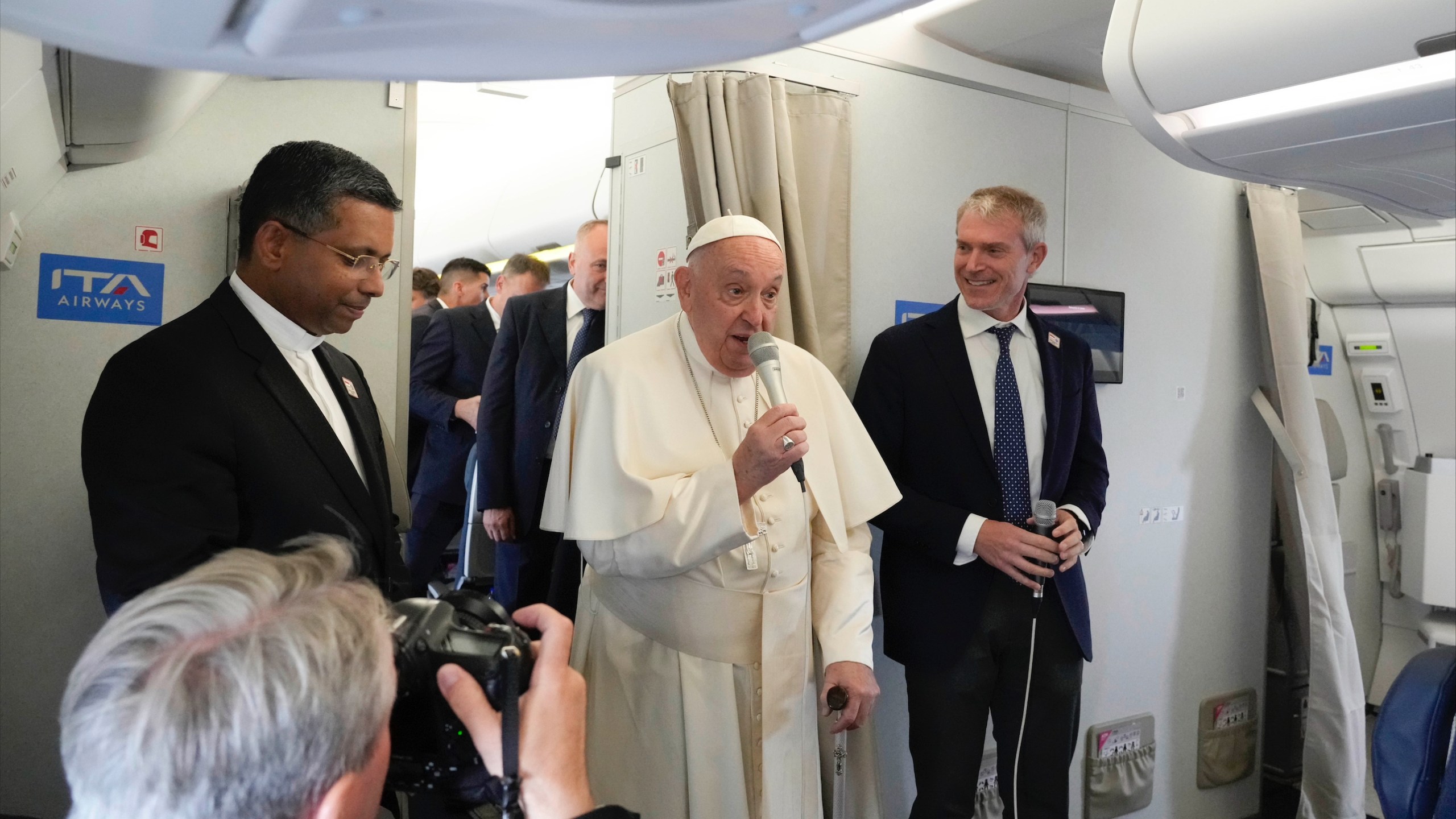 Pope Francis, center, flanked by his spokeperson Maeo Bruni, right, talks to journalists, Monday, Sept. 2, 2024, aboard the flight bound to Jakarta, Indonesia, where Francis will start his 12-day pastoral visit to Asia. Francis will clock 32,814 kilometers (20,390 miles) by air during his Sept. 2-13 visit to Indonesia, Papua New Guinea, East Timor and Singapore, far surpassing any of his previous 44 foreign trips and notching one of the longest papal trips ever, both in terms of days on the road and distances traveled. (AP Photo/Gregorio Borgia, pool)