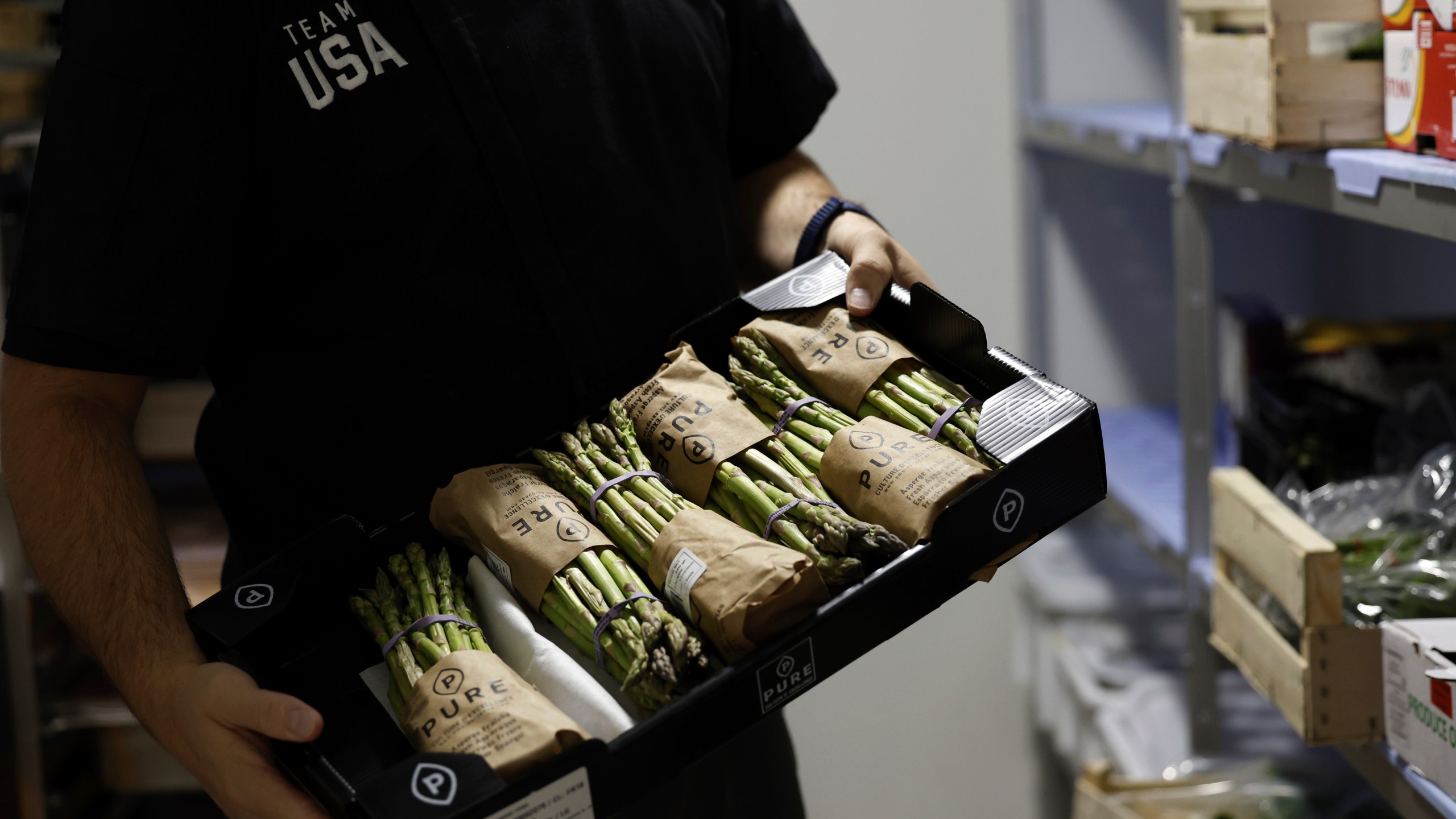 Brian Knutson, director of food and nutrition for the United States Olympic Paralympic Committee, holds up a crate of asparagus in the kitchen of the USOPC's High Performance Center on Saturday, Aug. 31, 2024. This is the first year that the HPC has been kept open for the Paralympic athletes. Knutson said that the quality of the local fruit and vegetables they were receiving were good. When they were in Tokyo, they realized that they were shipping raspberries from Oregon, Knutson said. (AP Photo/Nathalee Simoneau)