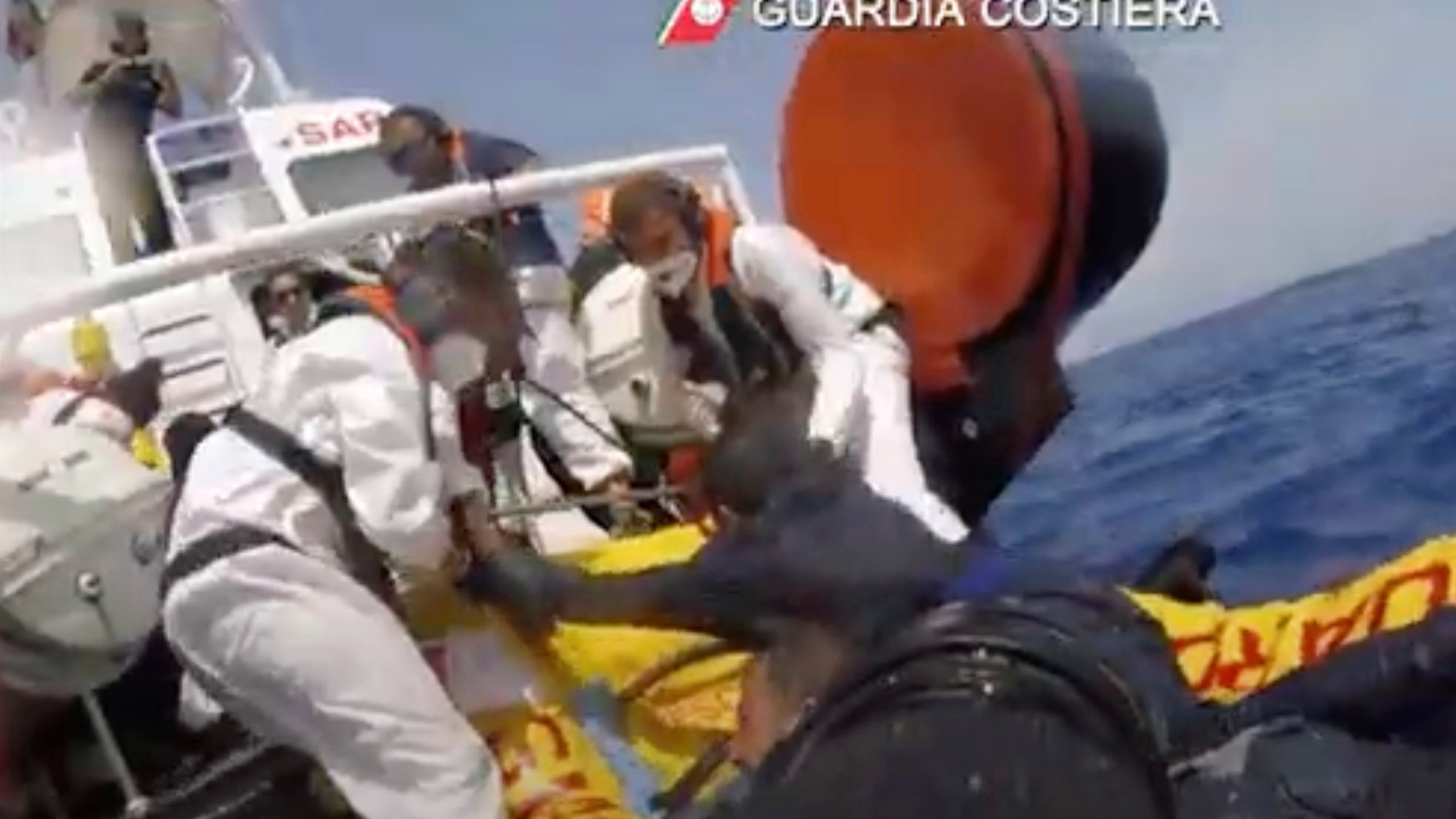 The image made from a video provided by the Italian coast guard shows a patrol boat rescuing migrants from a sinking ship off the coast of Lampedusa, Italy. (Italian Coast Guard via AP)