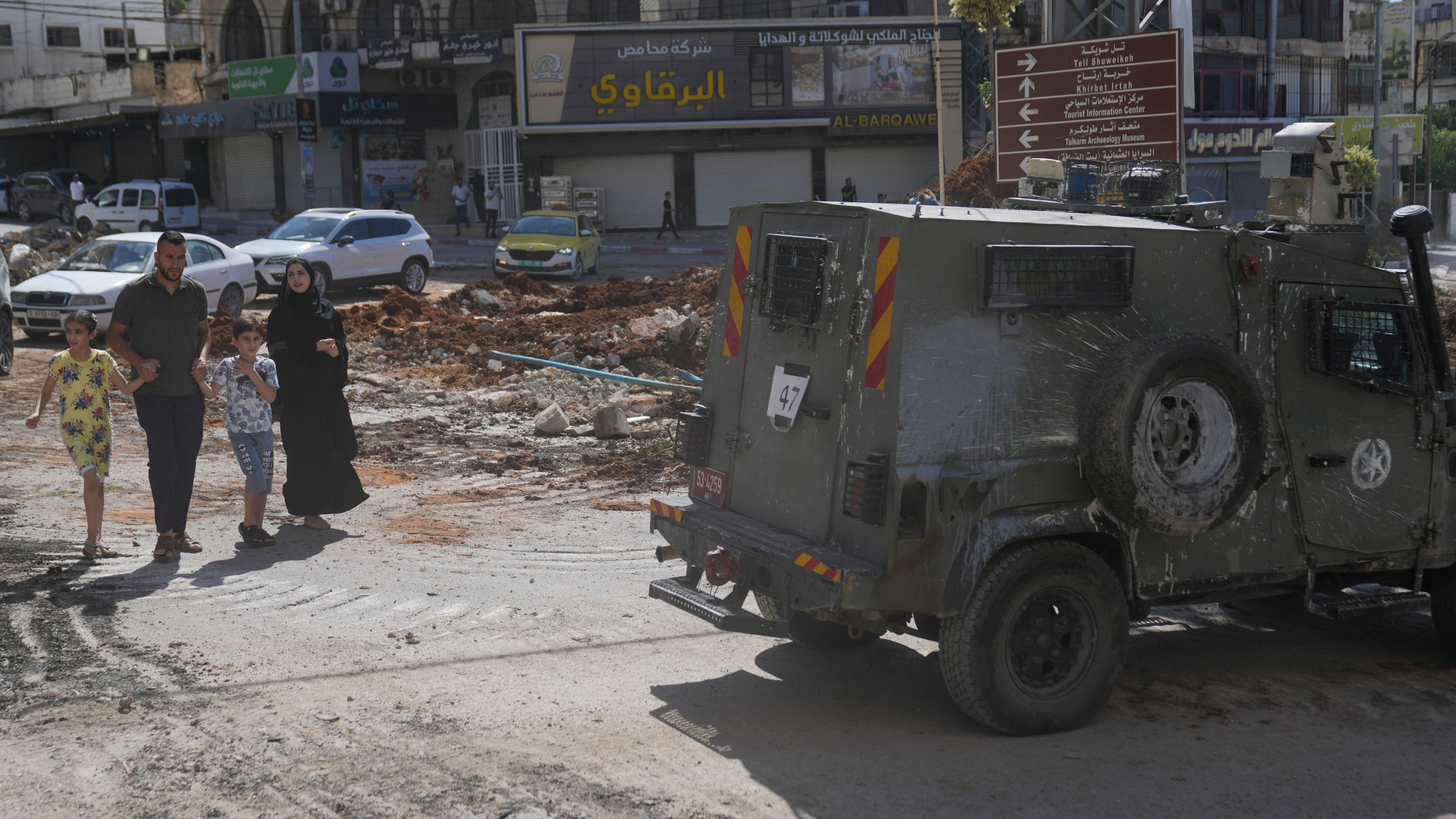 Palestinians walk past an Israeli armored vehicle during a military operation in the West Bank city of Tulkarem, Wednesday, Sept. 4, 2024. (AP Photo/ Nasser Nasser)