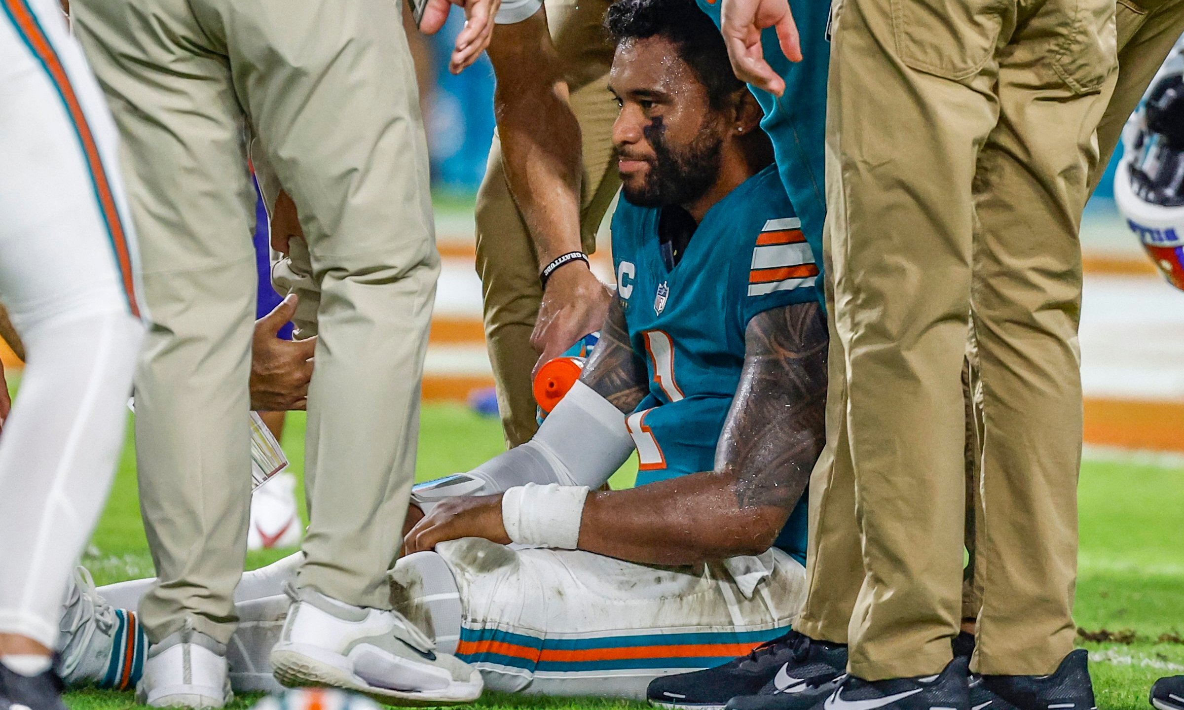 Miami Dolphins quarterback Tua Tagovailoa (1) sits on the field as he is attended to after an injury during the game against the Buffalo Bills in the second half of an NFL football game on Thursday, Sept. 12, 2024. (Al Diaz/Miami Herald via AP)