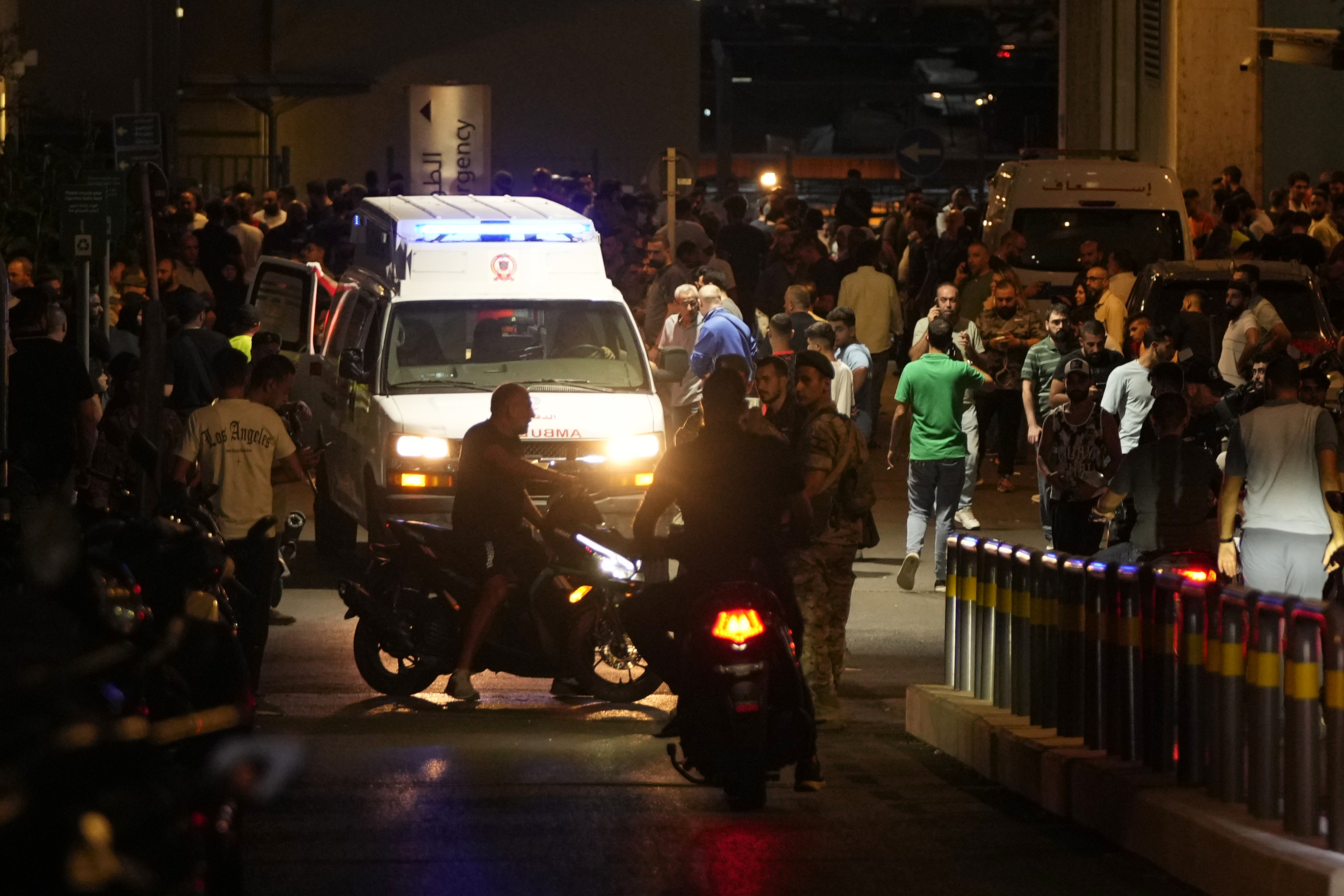 People gather around an ambulance carrying wounded people whose handheld pager exploded, at the emergency entrance of the American University hospital in Beirut, Lebanon, Tuesday, Sept. 17, 2024. (AP Photo/Hassan Ammar)