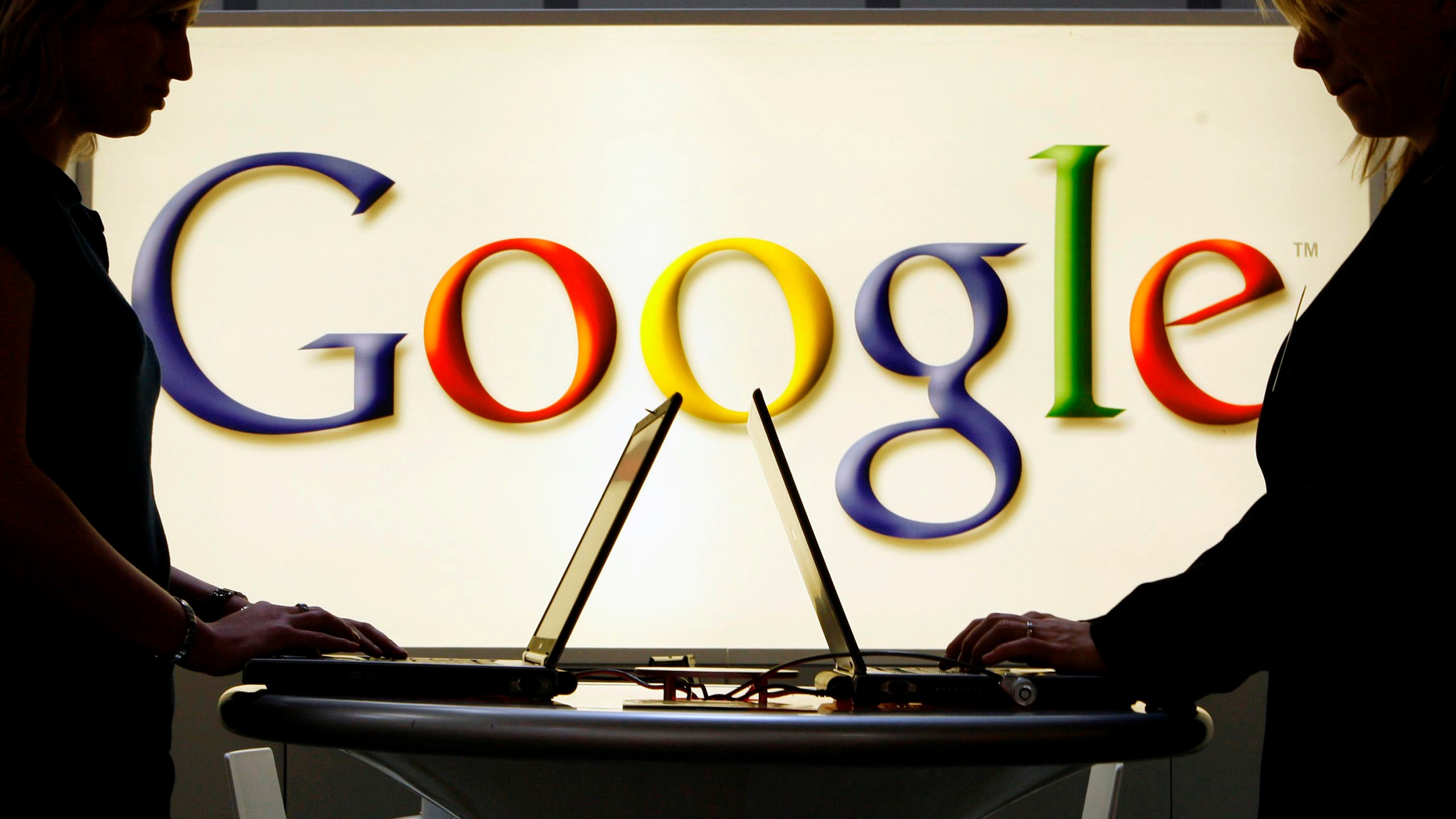 FILE - In this April 17, 2007 file photo, exhibitors work on laptop computers in front of an illuminated sign of the Google logo at the industrial fair Hannover Messe in Hanover, Germany. (AP Photo/Jens Meyer, File)