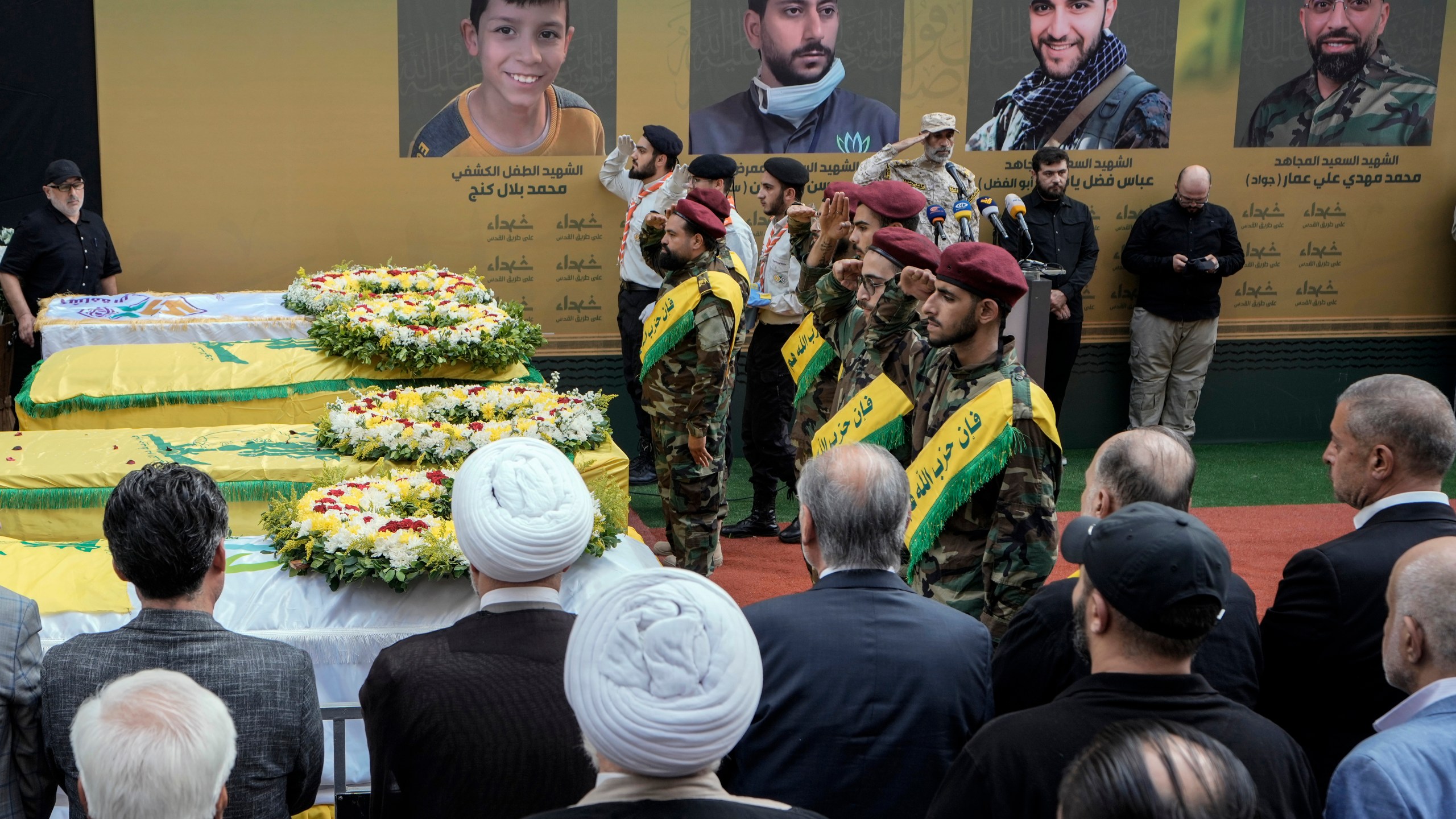 Hezbollah fighters salute as they stand next to the coffins of four victims who were killed Tuesday after their handheld pagers exploded, during their funeral procession in the southern suburb of Beirut, Lebanon, Wednesday, Sept. 18, 2024. (AP Photo/Bilal Hussein)