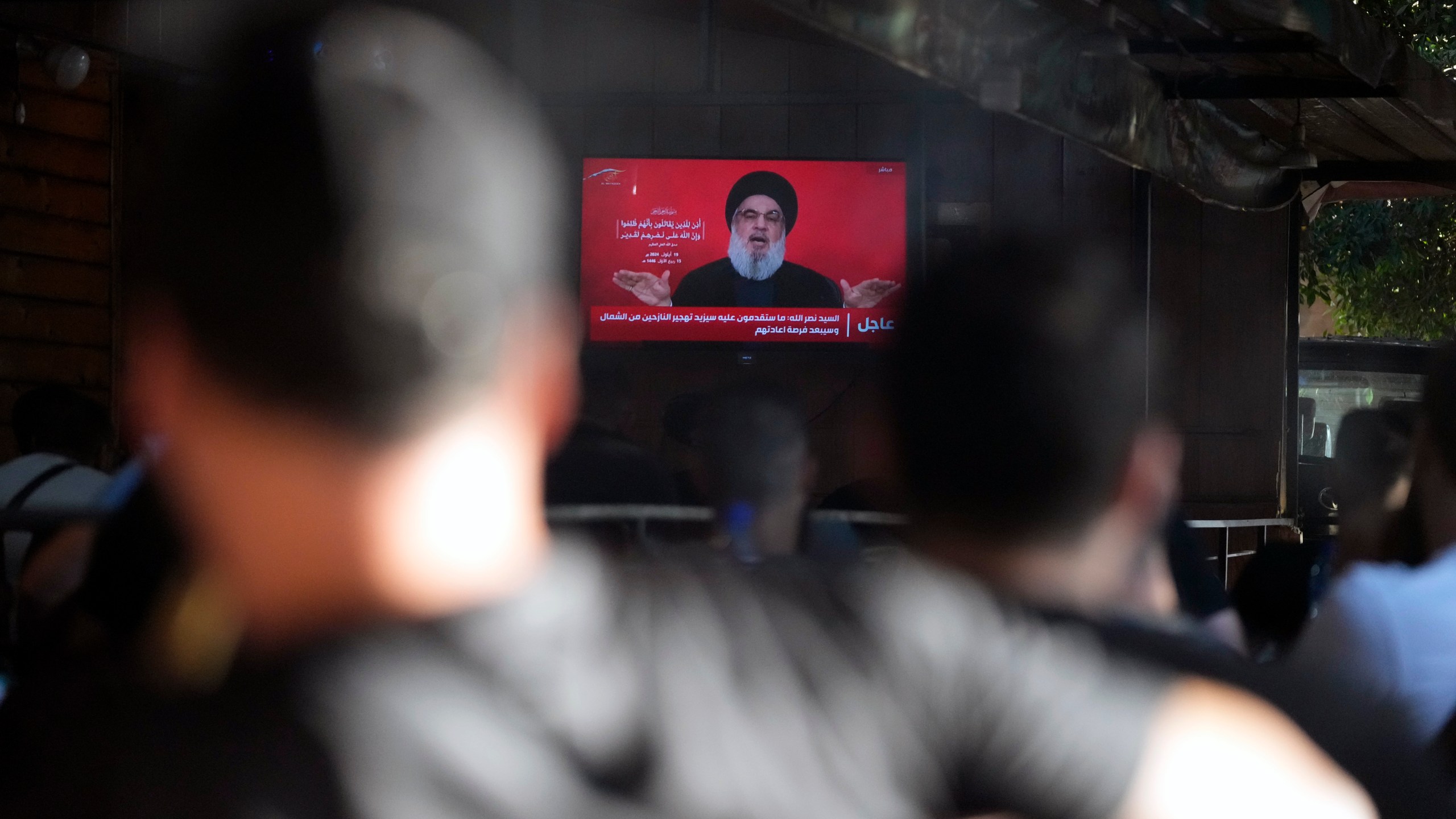 People watch the speech of Hezbollah leader Hassan Nasrallah on a tv screen as they sit in a cafe in the southern suburbs of Beirut, Thursday, Sept. 19, 2024. (AP Photo/Hassan Ammar)