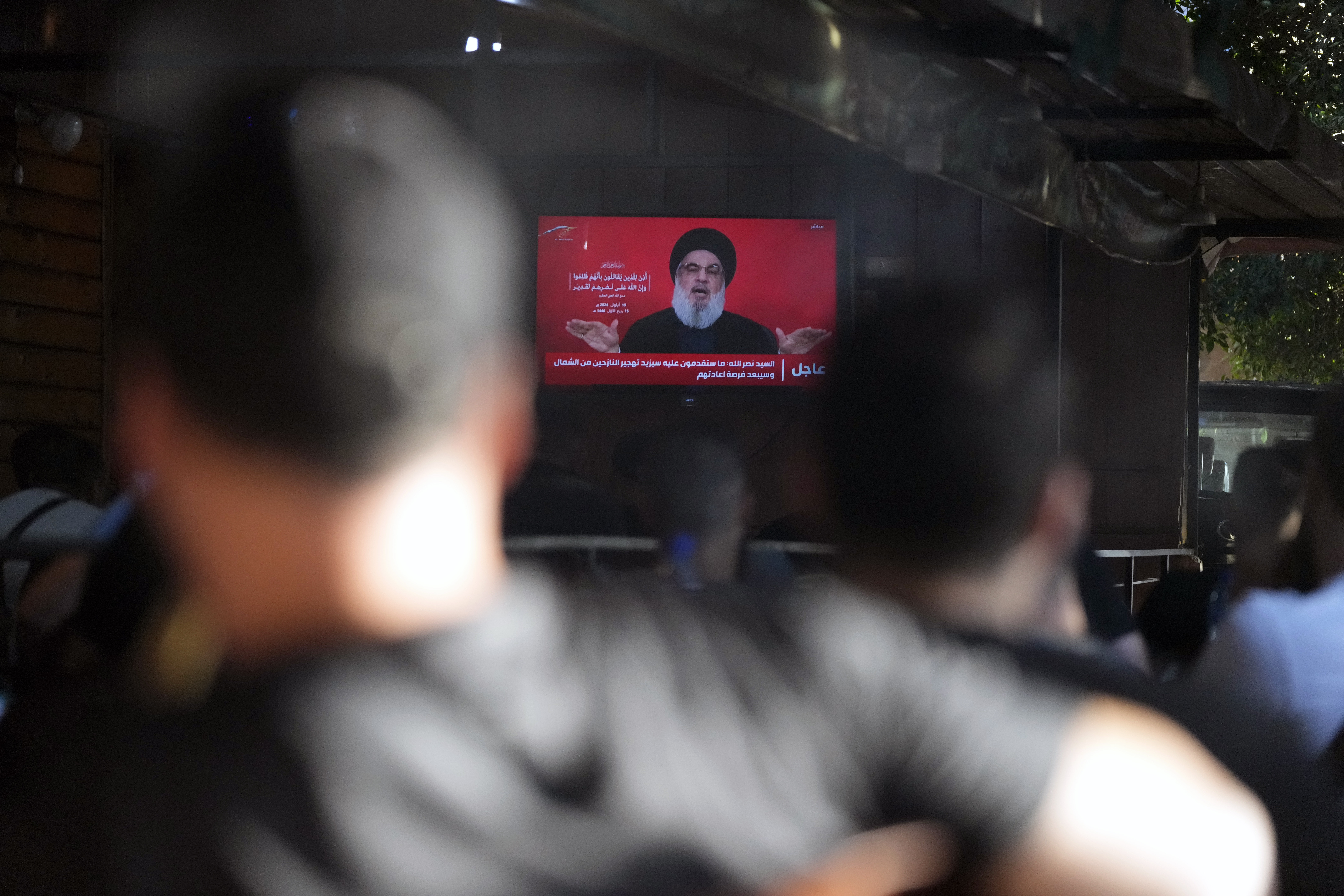 People watch the speech of Hezbollah leader Hassan Nasrallah on a tv screen as they sit in a cafe in the southern suburbs of Beirut, Thursday, Sept. 19, 2024. (AP Photo/Hassan Ammar)