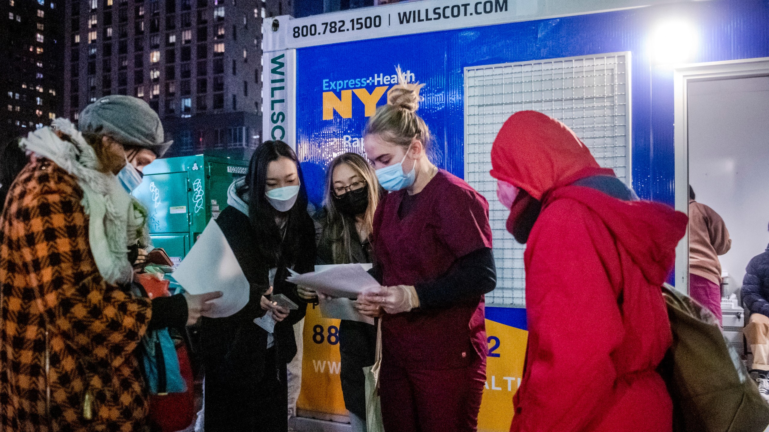 FILE - People check their rapid COVID-19 test results outside of a testing site on the Lower East Side of Manhattan, on Dec. 21, 2021, in New York. (AP Photo/Brittainy Newman, File)