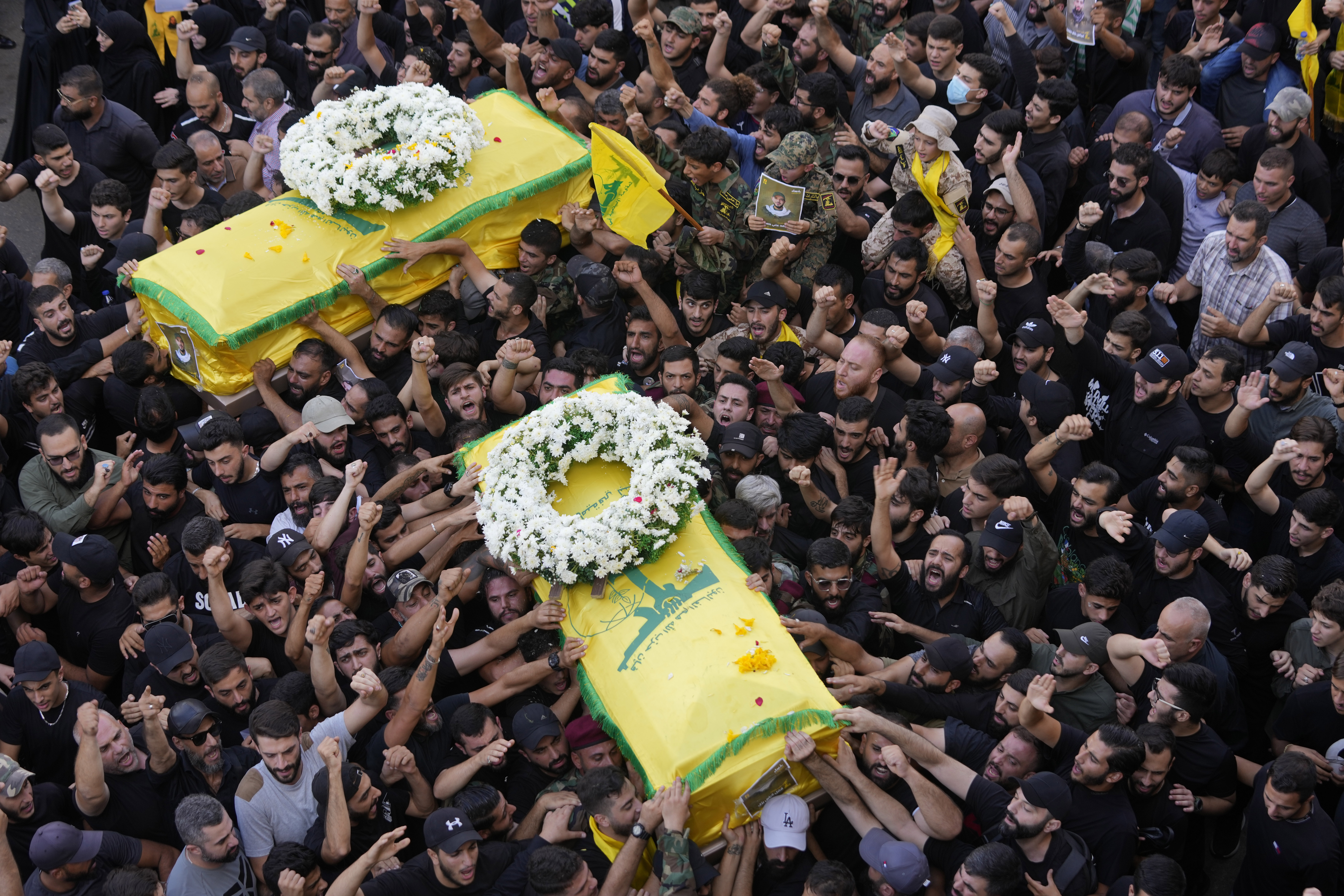 Hezbollah members carry the coffins of two of their comrades who were killed on Wednesday when a handheld device exploded, during a funeral procession in the southern suburbs of Beirut, Thursday, Sept. 19, 2024. (AP Photo/Hussein Malla)