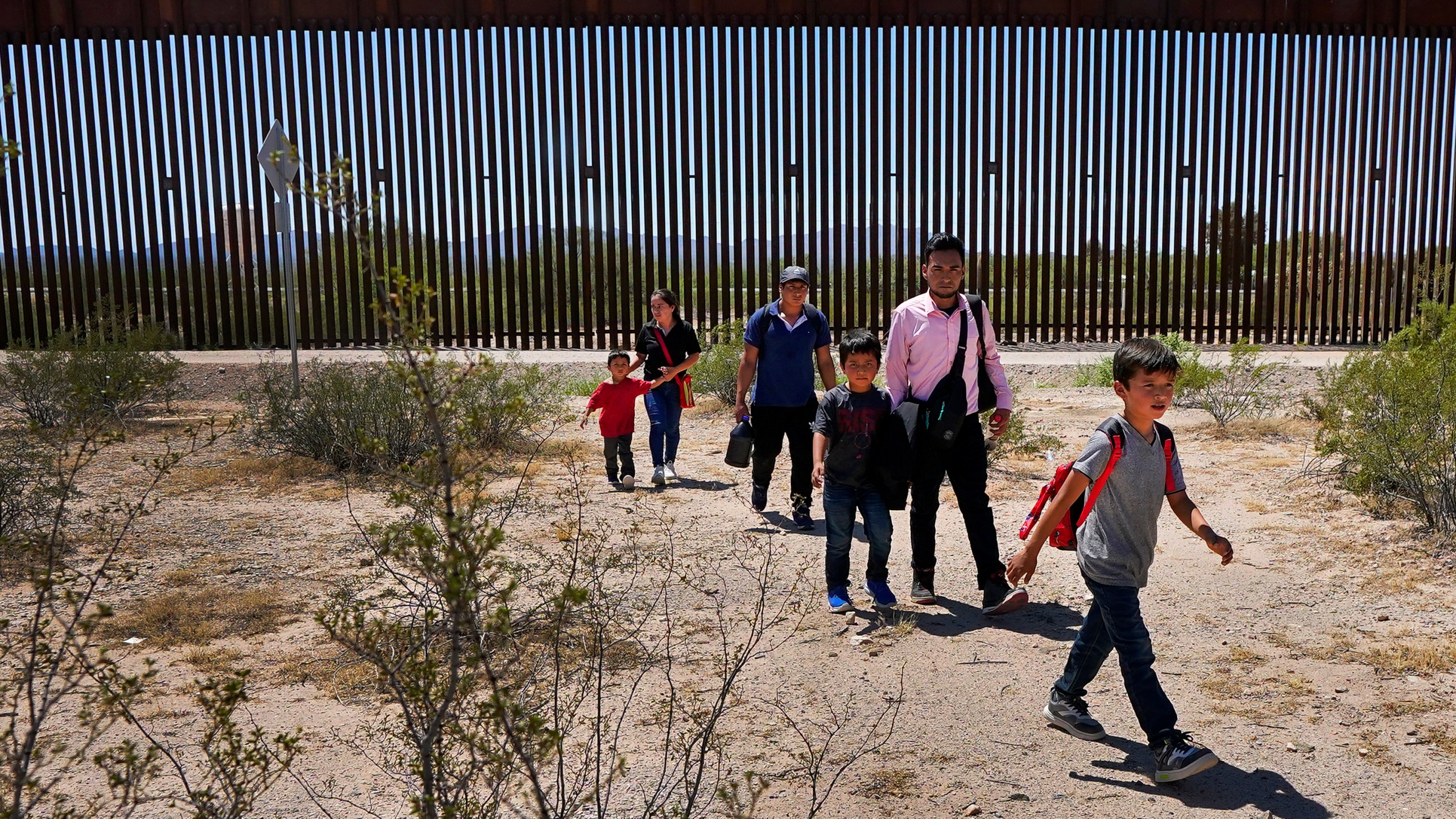 FILE - A family of five claiming to be from Guatemala and a man stating he was from Peru, in pink shirt, walk through the desert after crossing the border wall in the Tucson Sector of the U.S.-Mexico border, Tuesday, Aug. 29, 2023, in Organ Pipe Cactus National Monument near Lukeville, Ariz. (AP Photo/Matt York, File)