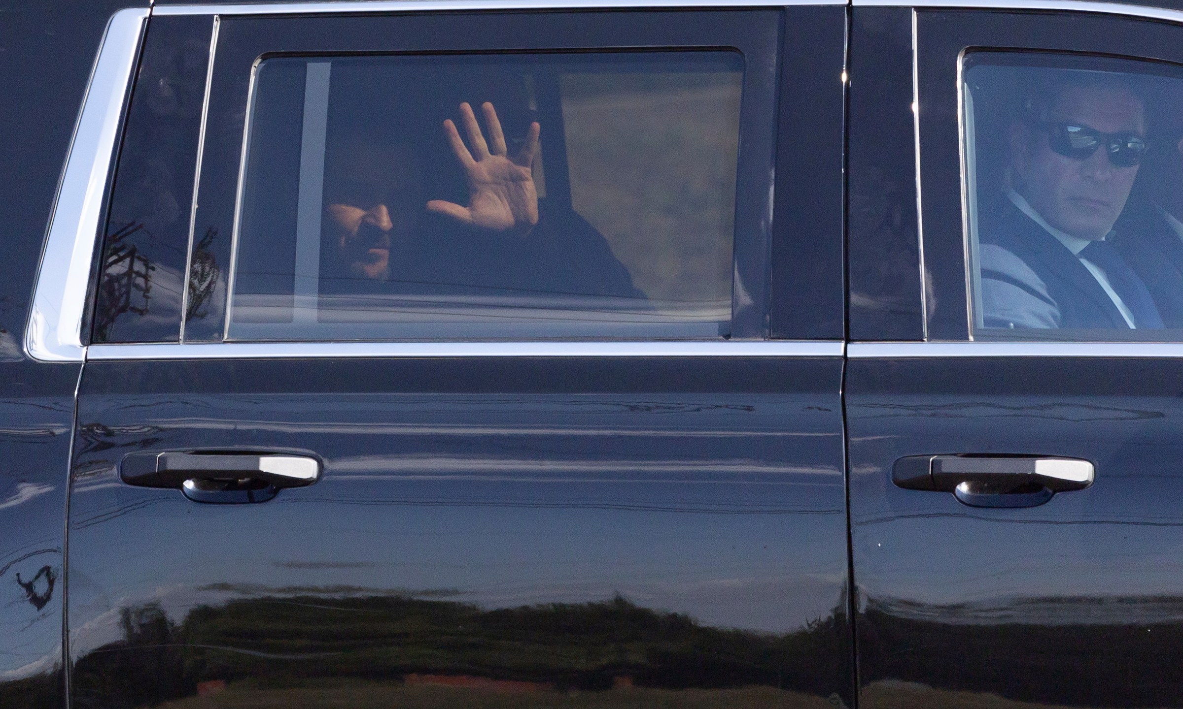 Ukrainian President Volodymyr Zelenskyy waves from the back seat of a U.S. Secret Service vehicle as his motorcade departs the Wilkes-Barre/Scranton International Airport in Pittston Township, Pa. en route to the Scranton Army Ammunition Plant in Scranton, Pa. on Sunday, Sept. 22, 2024. (Christopher Dolan/The Times-Tribune via AP)