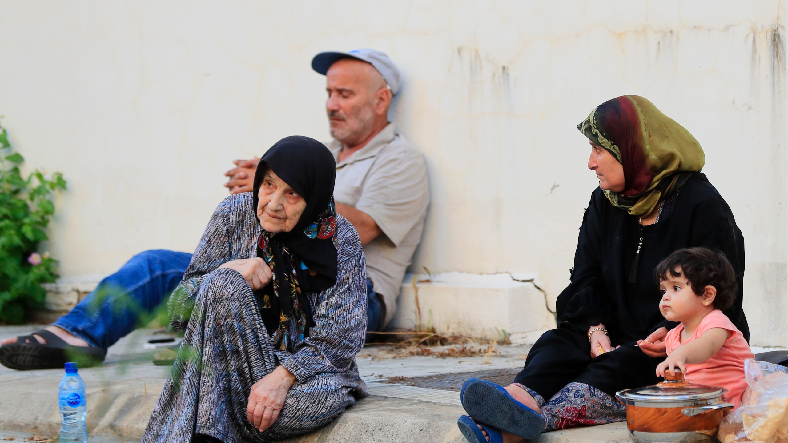 People fleeing the southern villages amid ongoing Israeli airstrikes, sit on the sidewalk outside a school in Sidon, Monday, Sept. 23, 2024. (AP Photo/Mohammed Zaatari)