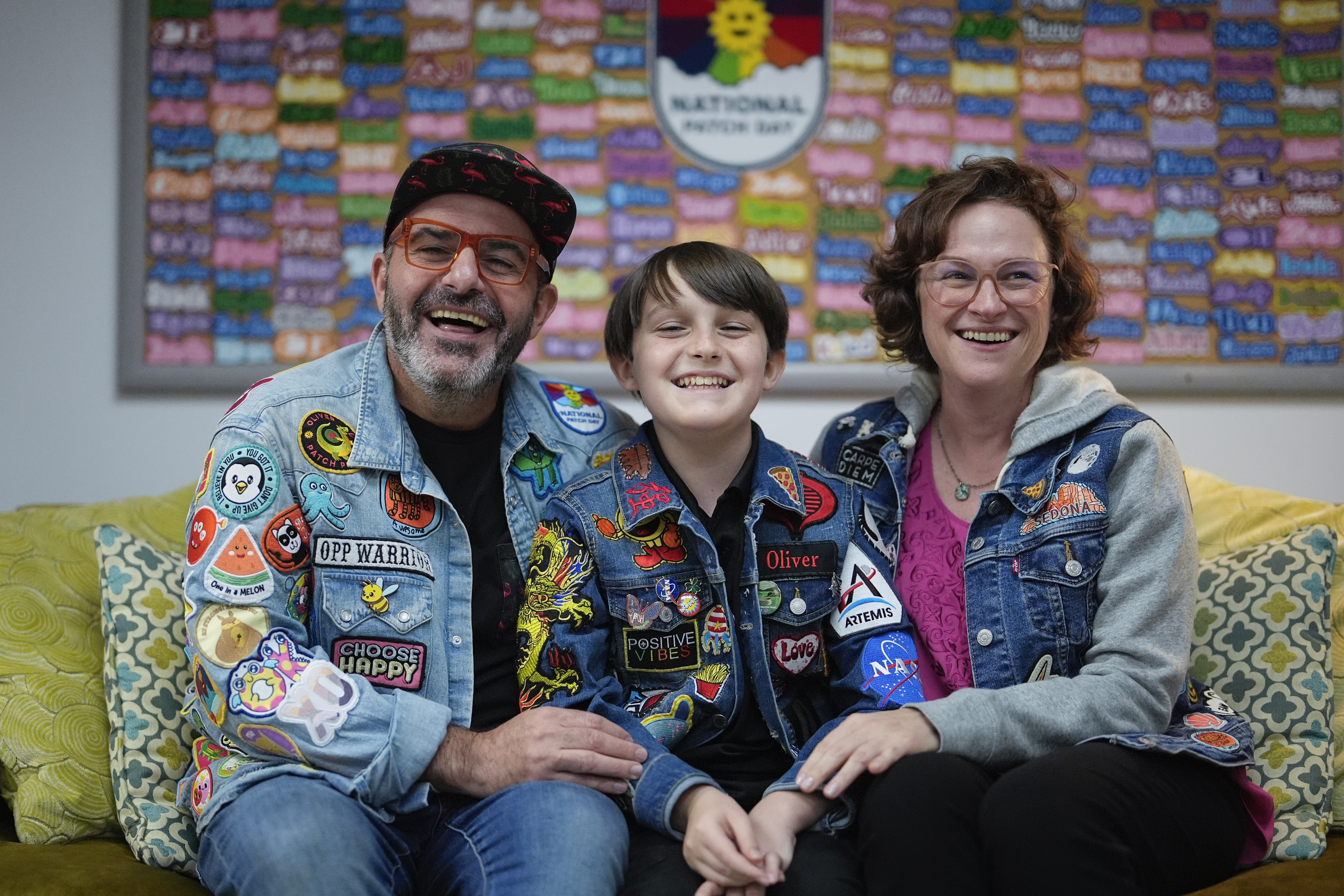 Brian Burkhardt, left, and Trisha Brookbank, right, pose for a picture with their son Oliver Burkhardt, 13, in the offices of the Oliver Patch Project, Wednesday, Sept. 4, 2024, in Miami. (AP Photo/Rebecca Blackwell)