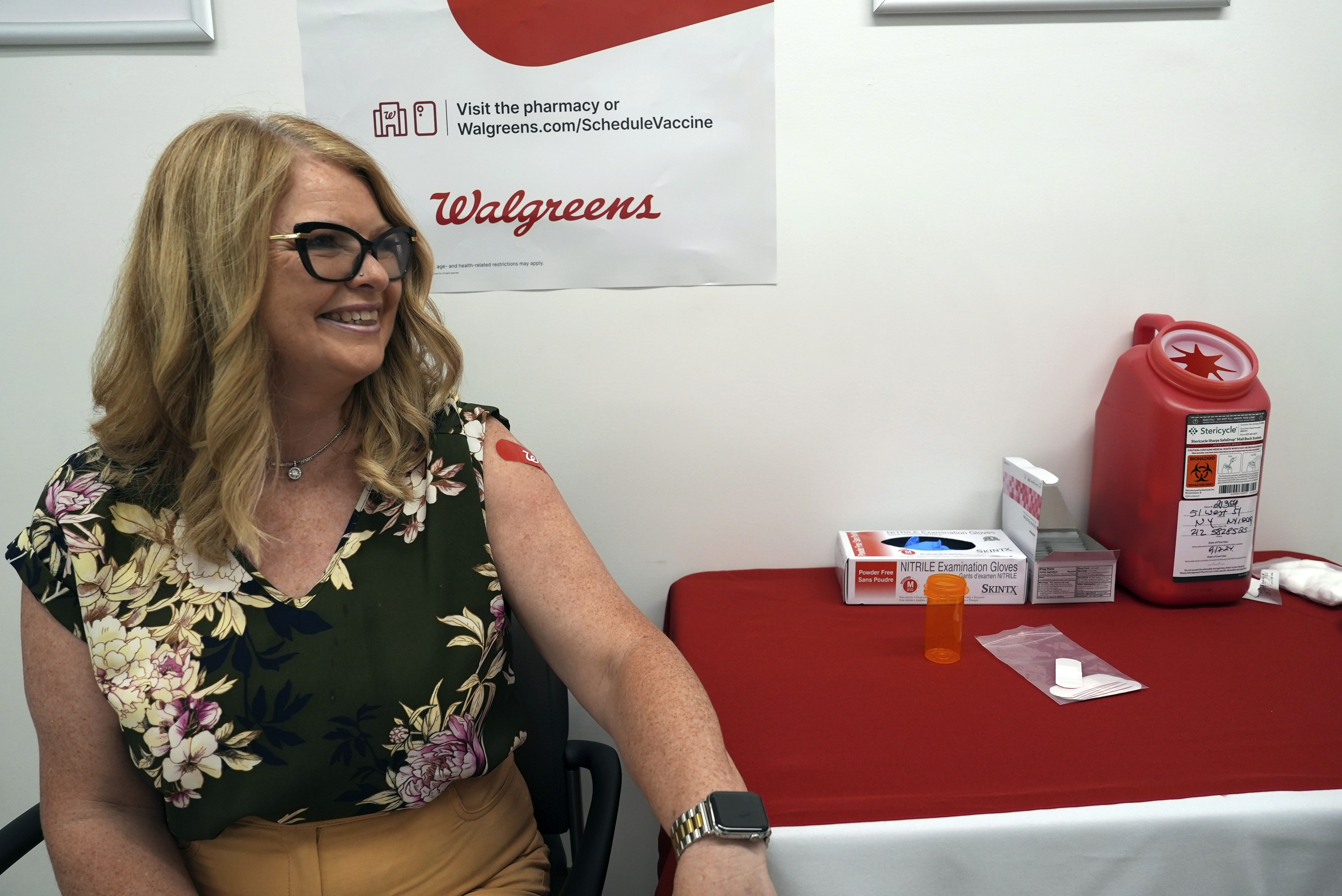 Kelly Vazquez sits down after receiving COVID-19 and flu shots at a pharmacy in New York, on Tuesday, Sept. 24, 2024. (AP Photo/Mary Conlon)