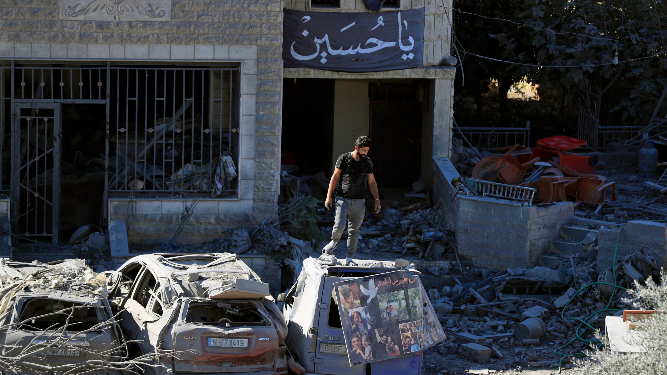 A man stands on top of a damaged car at the site of an Israeli airstrike in Saksakieh, south Lebanon, Thursday, Sept. 26, 2024. (AP Photo/Mohammed Zaatari)