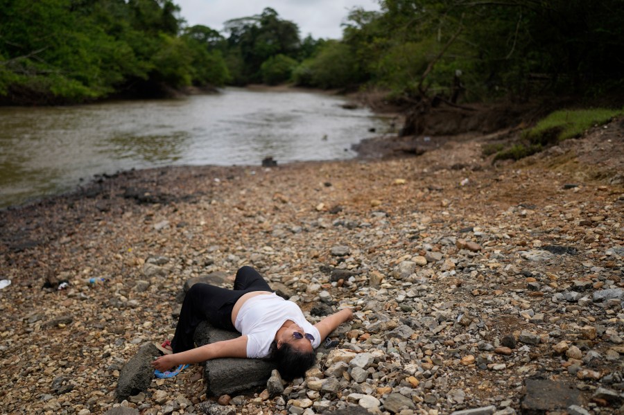 Marisol Jaime, from Venezuela, lies on the shore after disembarking from a boat in Lajas Blancas, Panama, Thursday, Sept. 26, 2024, following her trek through the Darién Gap from Colombia in hopes of reaching the U.S. (AP Photo/Matias Delacroix)