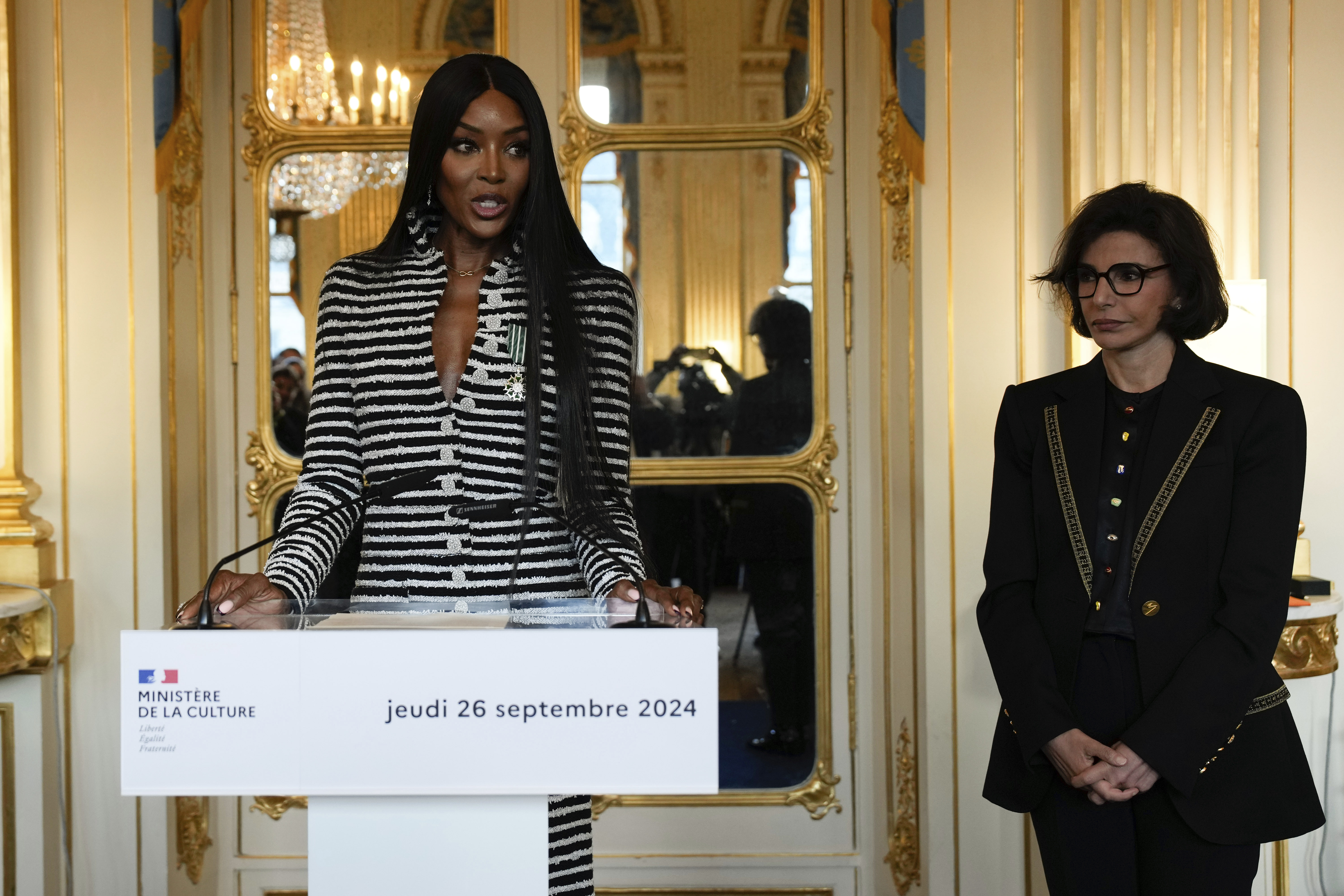 Naomi Campbell delivers a speech after being awarded with the medal of "Chevalier de l'Ordres des Arts et des Lettres", by French Culture Minister Rachida Dati, right, at the Culture ministry, in Paris, Thursday, Sept. 26, 2024. (AP Photo/Louise Delmotte)