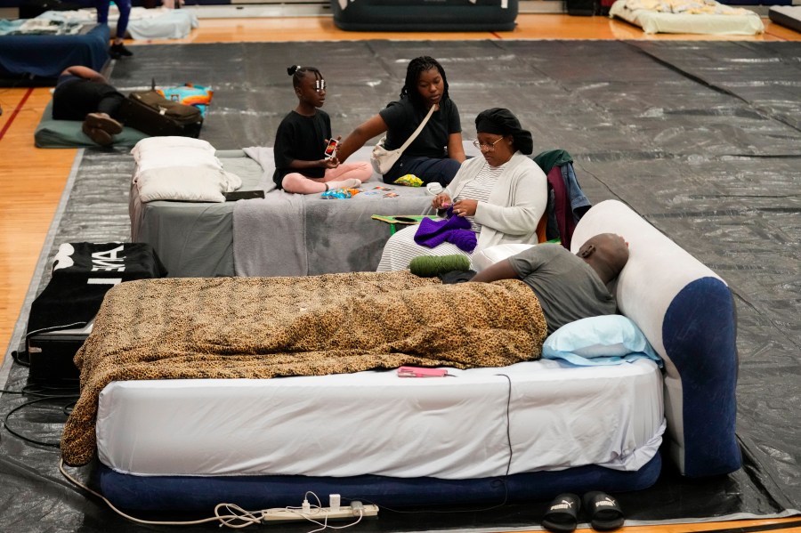 Sharonda and Victor Davis, of Tallahassee, sit with their children Victoria background left, and Amaya, background right, inside a hurricane evacuation shelter at Fairview Middle School, ahead of Hurricane Helene, expected to make landfall here today, in Leon County, Fla., Thursday, Sept. 26, 2024. (AP Photo/Gerald Herbert)