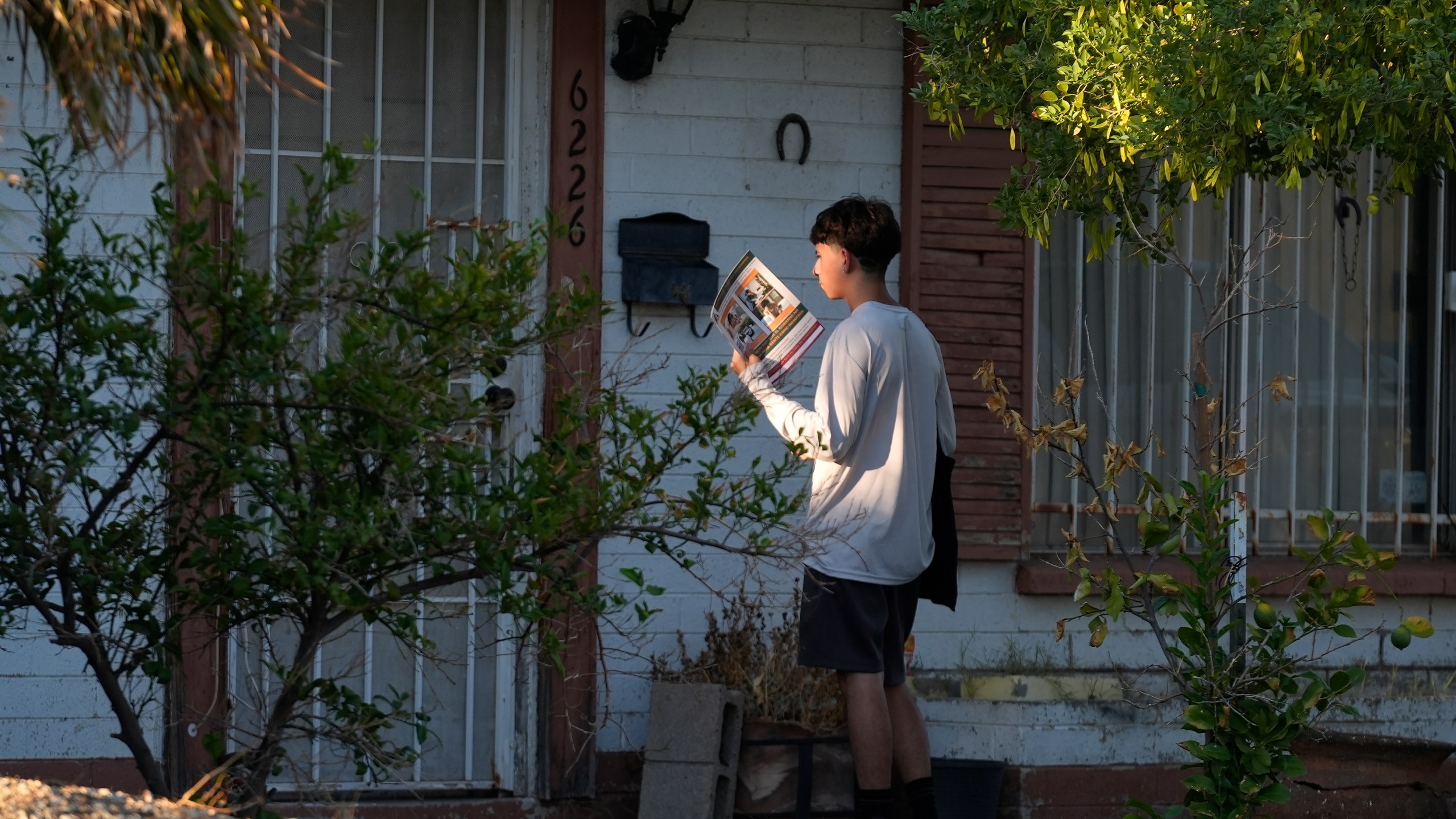 Poder In Action canvasser Andrew Chavez goes door-to-door during a neighborhood canvassing outreach Tuesday, Sept. 3, 2024, in Phoenix. (AP Photo/Ross D. Franklin)