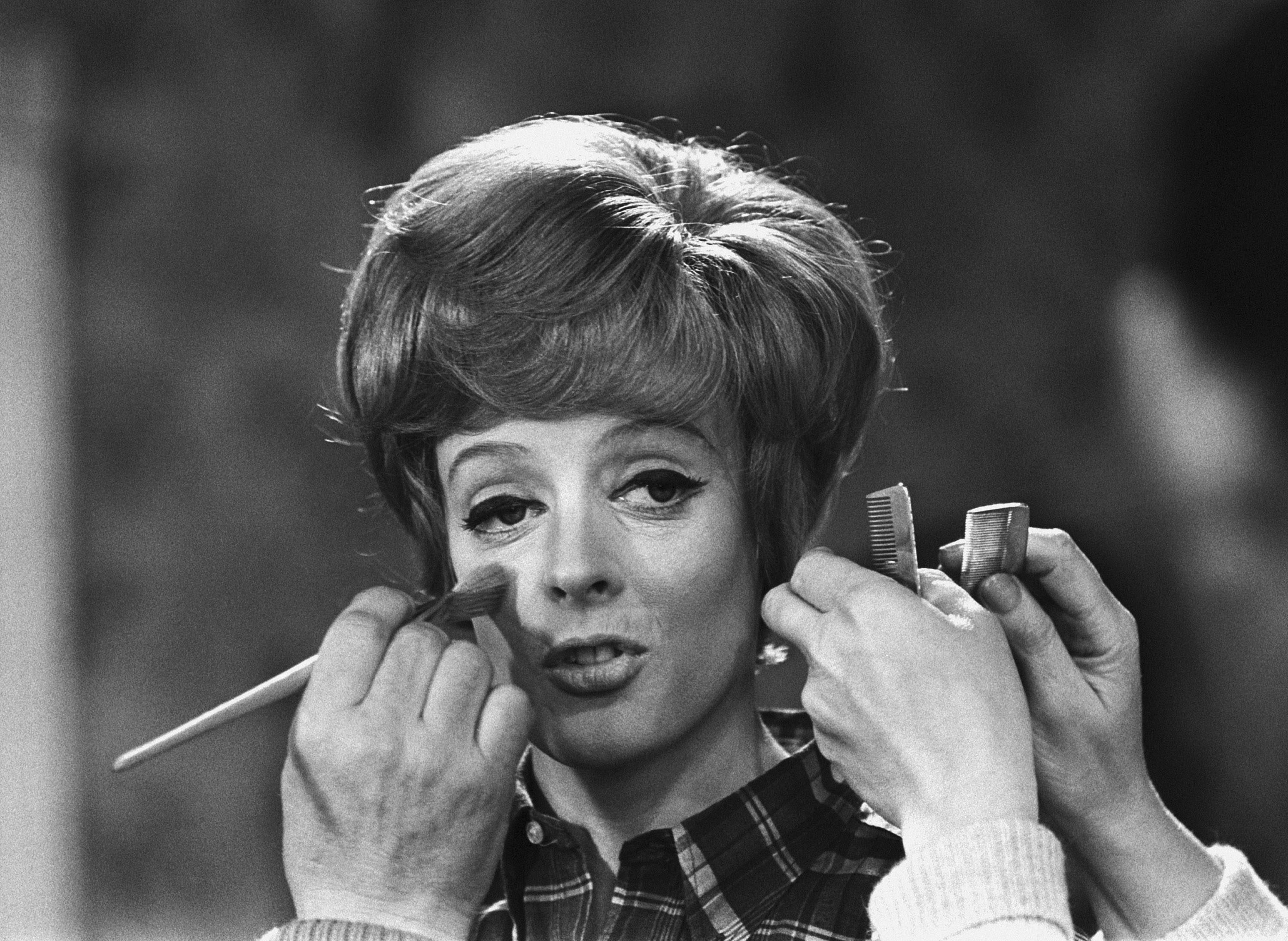 FILE - Make up and hair artists add the finishing touches to British actress Maggie Smith before she faces the camera with Peter Ustinov in the comedy 'Hot Millions' being filmed at Elstree Studios, England, Jan. 12, 1968. Smith has died aged 89. (AP Photo/Bob Dear, File)