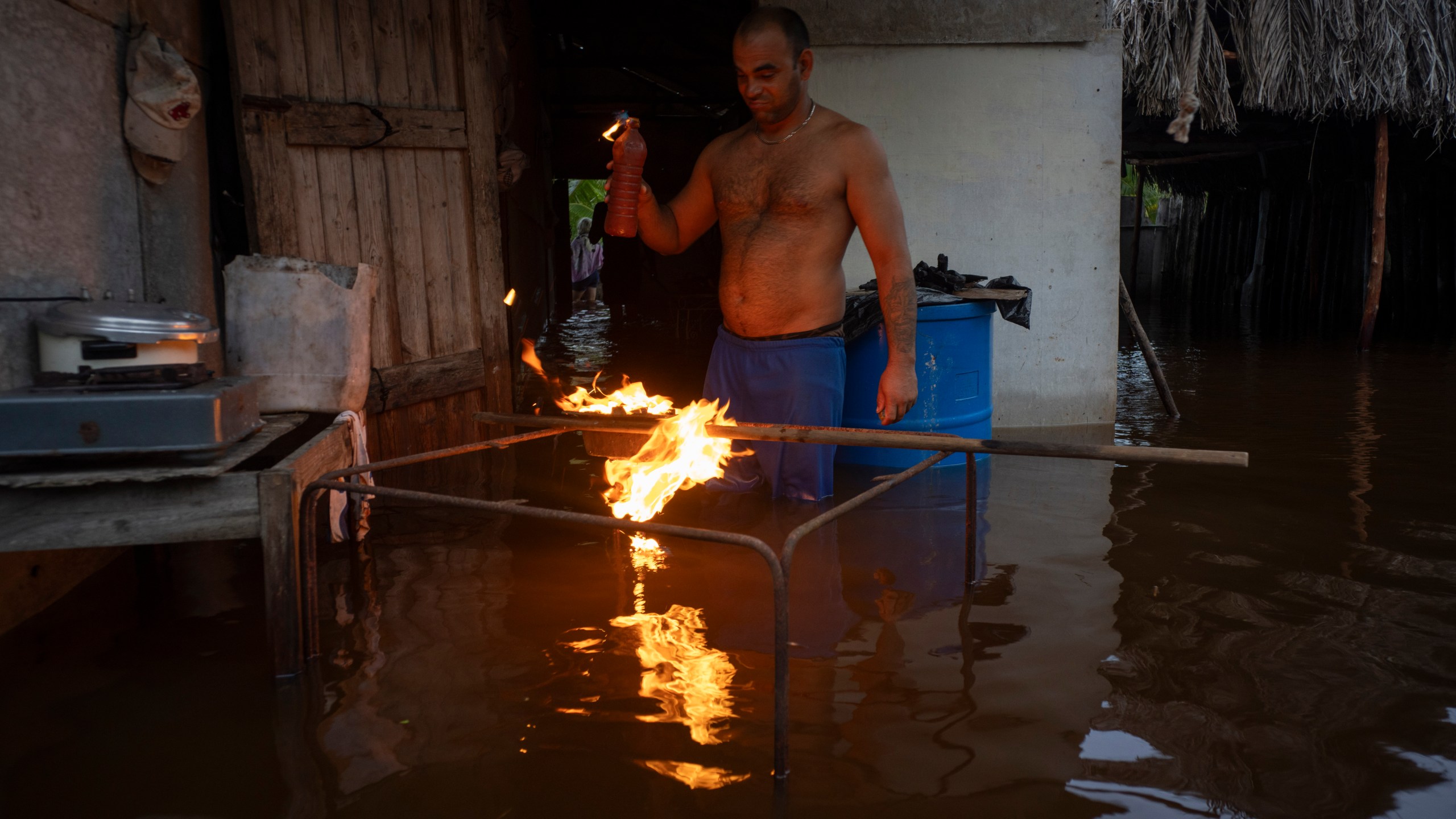 A man lights charcoal to cook dinner in his flooded home after the passage of Hurricane Helene in Guanimar, Artemisa province, Cuba, Sept. 25, 2024. (AP Photo/Ramon Espinosa)