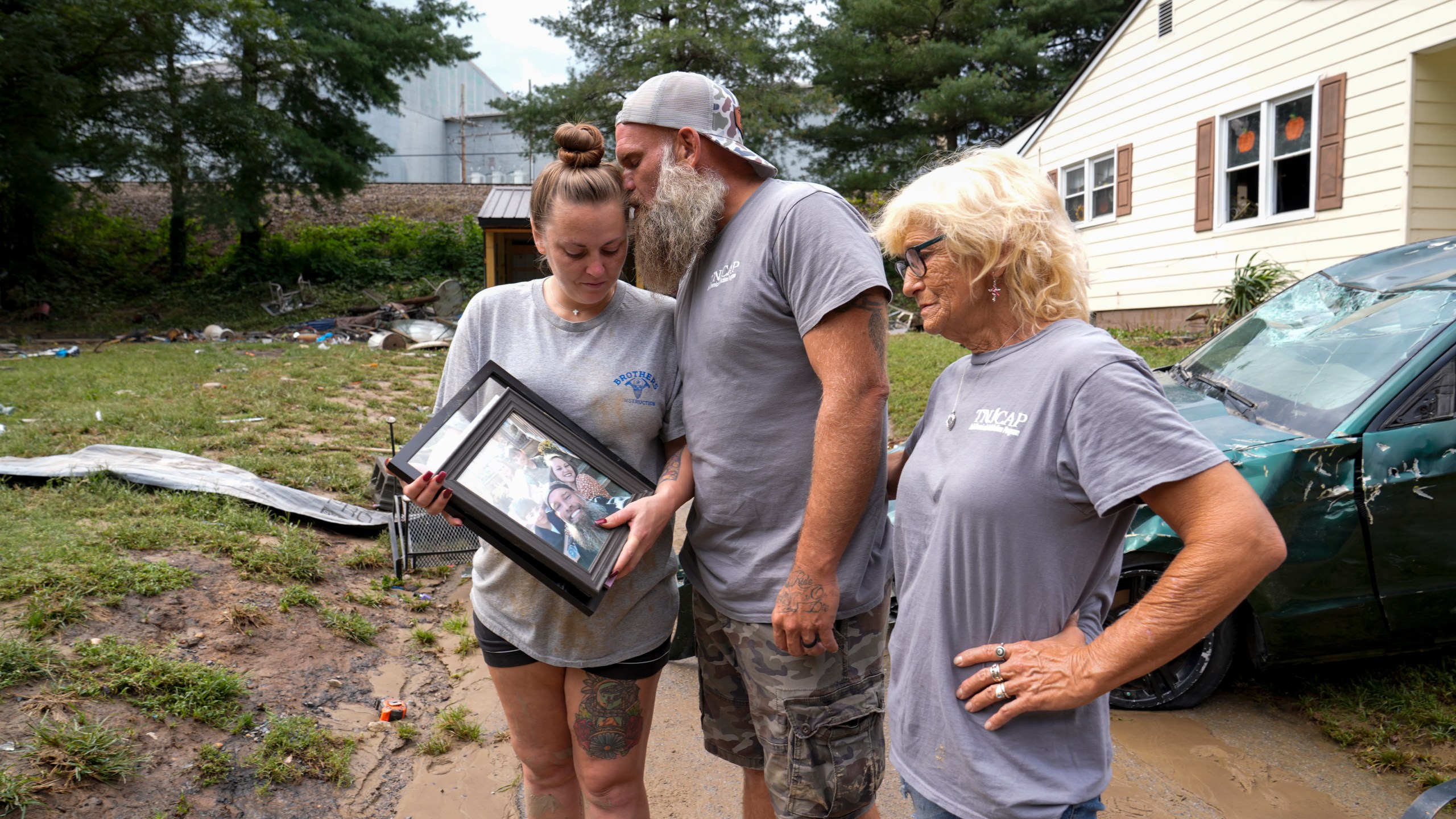 Dustin Bentley, center, kisses his wife Jennifer Bentley, left, after retrieving family photos from their flood-damaged home in the aftermatch of Hurricane Helene as his mother Janet Sams looks on Saturday, Sept. 28, 2024, in Newport, Tenn. (AP Photo/George Walker IV)