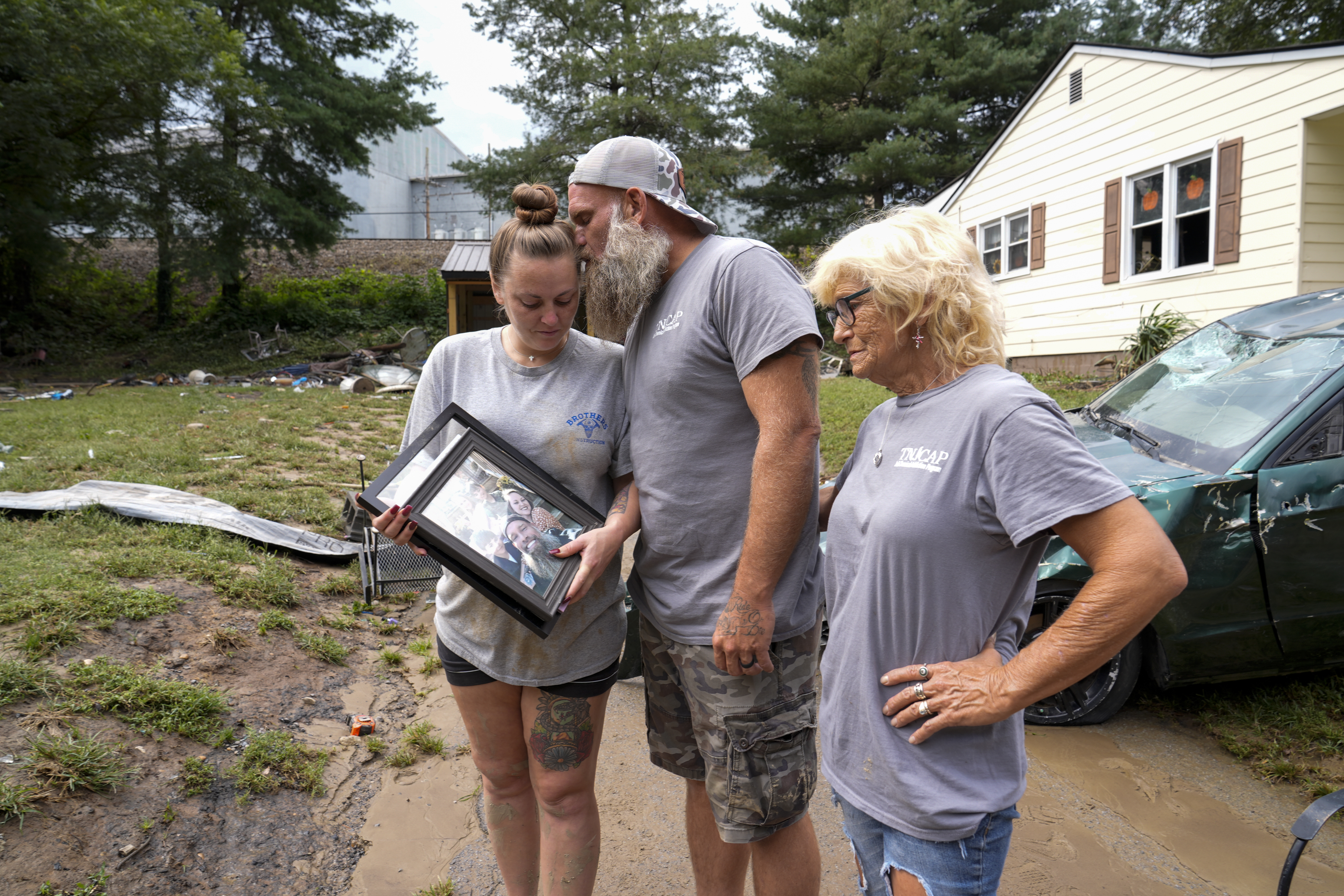 Dustin Bentley, center, kisses his wife Jennifer Bentley, left, after retrieving family photos from their flood-damaged home in the aftermatch of Hurricane Helene as his mother Janet Sams looks on Saturday, Sept. 28, 2024, in Newport, Tenn. (AP Photo/George Walker IV)