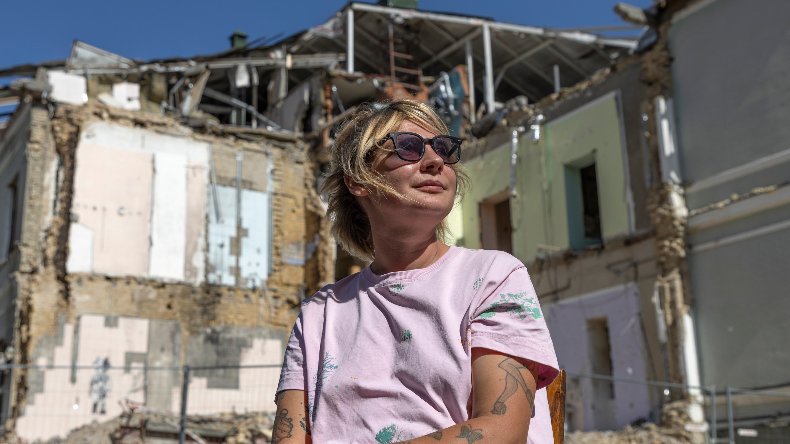 Olha Bulkina, 35, co-founder of the "Bureau of Smiles and Support" sits in front of Okhmatdyt children's hospital in Kyiv, Ukraine Saturday Sept. 14, 2024 which was destroyed after a Russian missile strike on July 8. (AP Photo/Anton Shtuka)