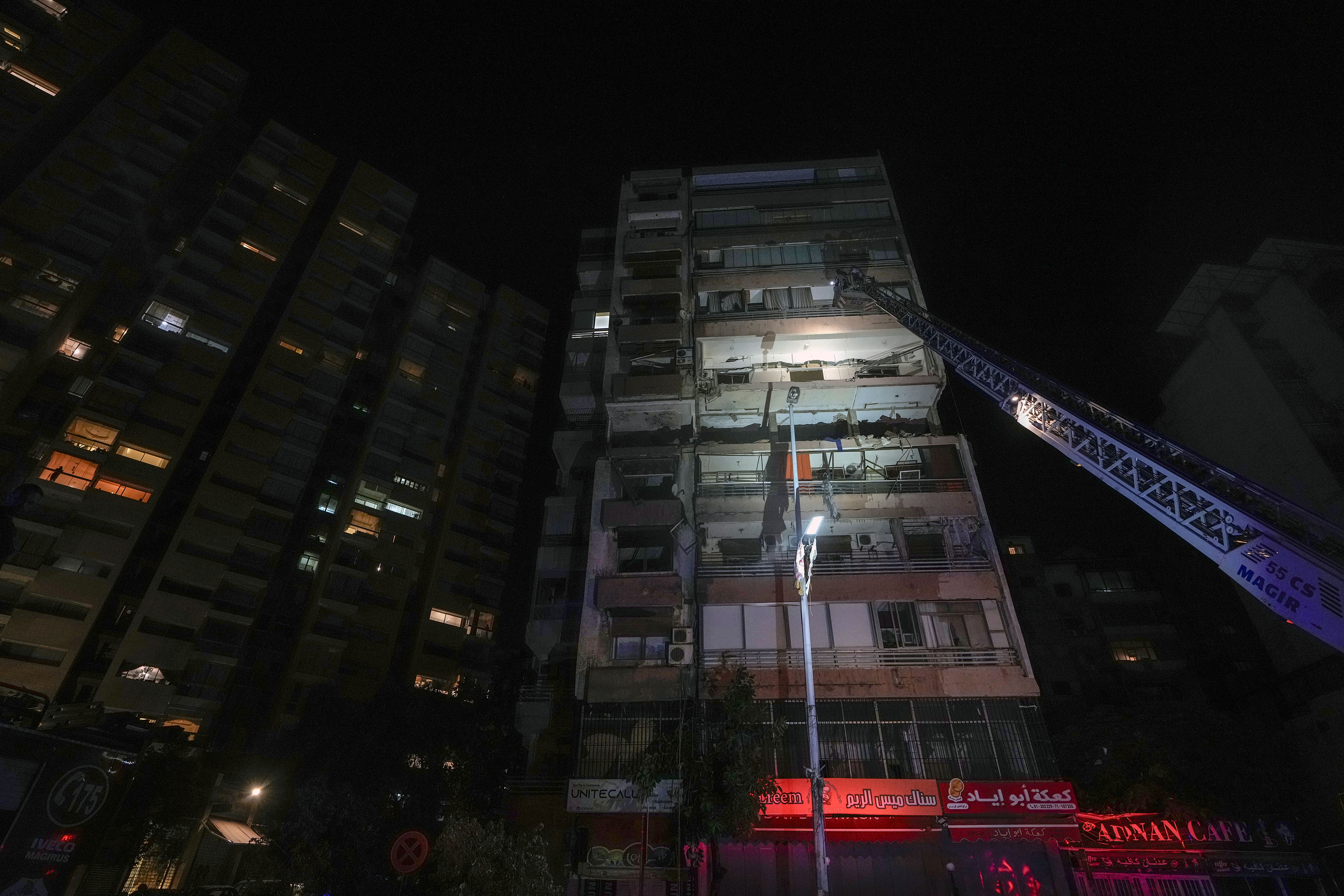 A fire engine ladder extends up a building that was hit in an apparent Israeli airstrike, in central Beirut, Lebanon, early Monday, Sept. 30, 2024. (AP Photo/Bilal Hussein)