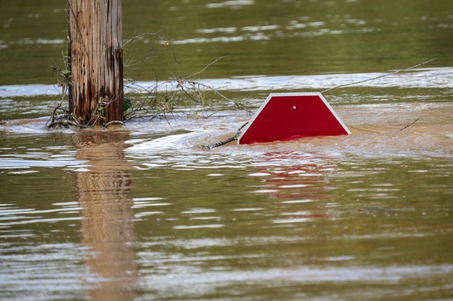 FILE - A stop sign is barely visible in floodwaters of a parking lot after torrential rain from Hurricane Helene, Saturday, Sept. 28, 2024, in Morganton, N.C. (AP Photo/Kathy Kmonicek, File)