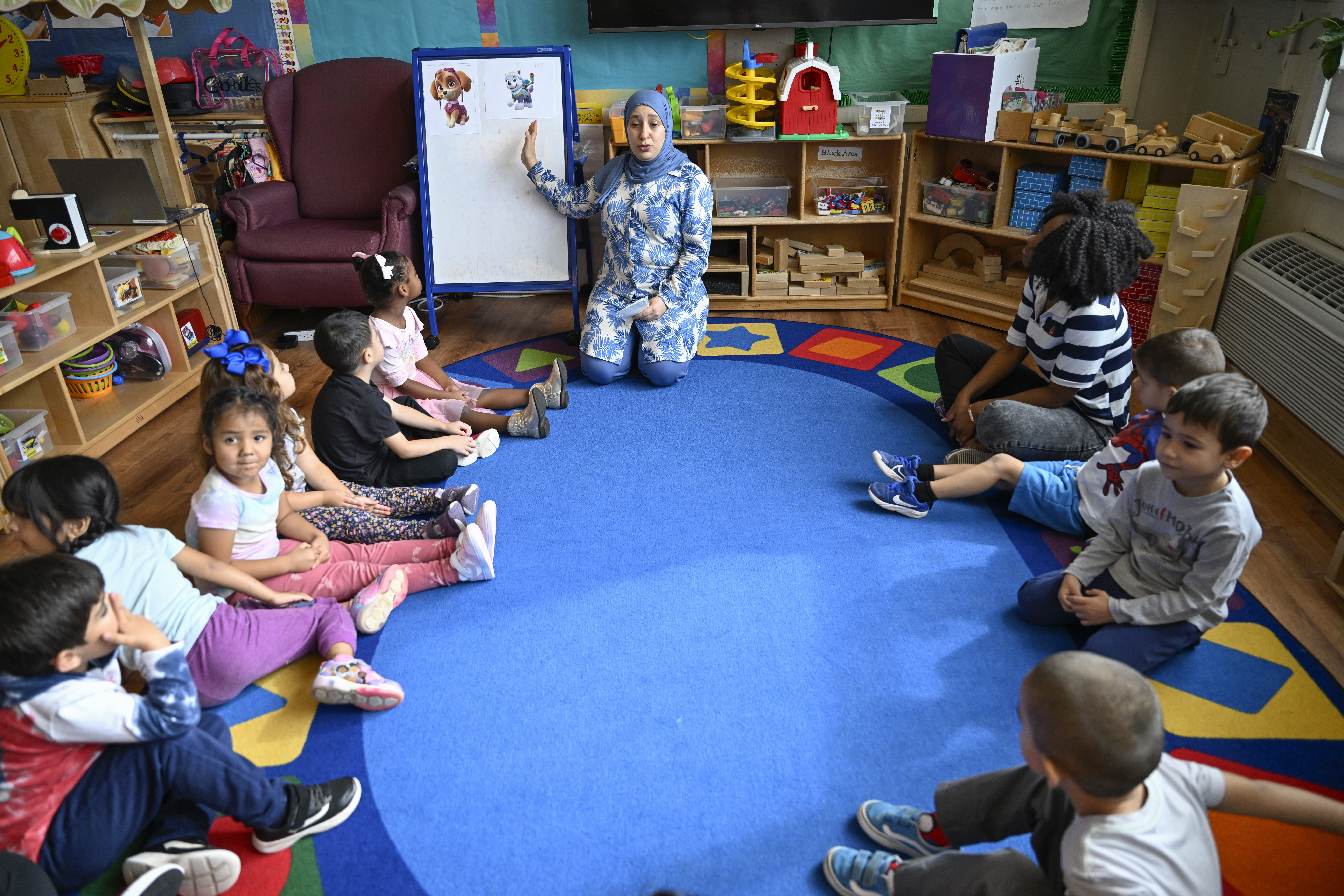 Preschool teacher Tinhinane Meziane, center, instructs to her students on how to vote the most popular character of the TV show PAW Patrol at the ACCA Child Development Center, Thursday, Sept. 19, 2024, in Annandale, Va. The students are getting foundational lessons on how to live in a democracy by allowing them to regularly vote on different things through out the day. (AP Photo/John McDonnell)