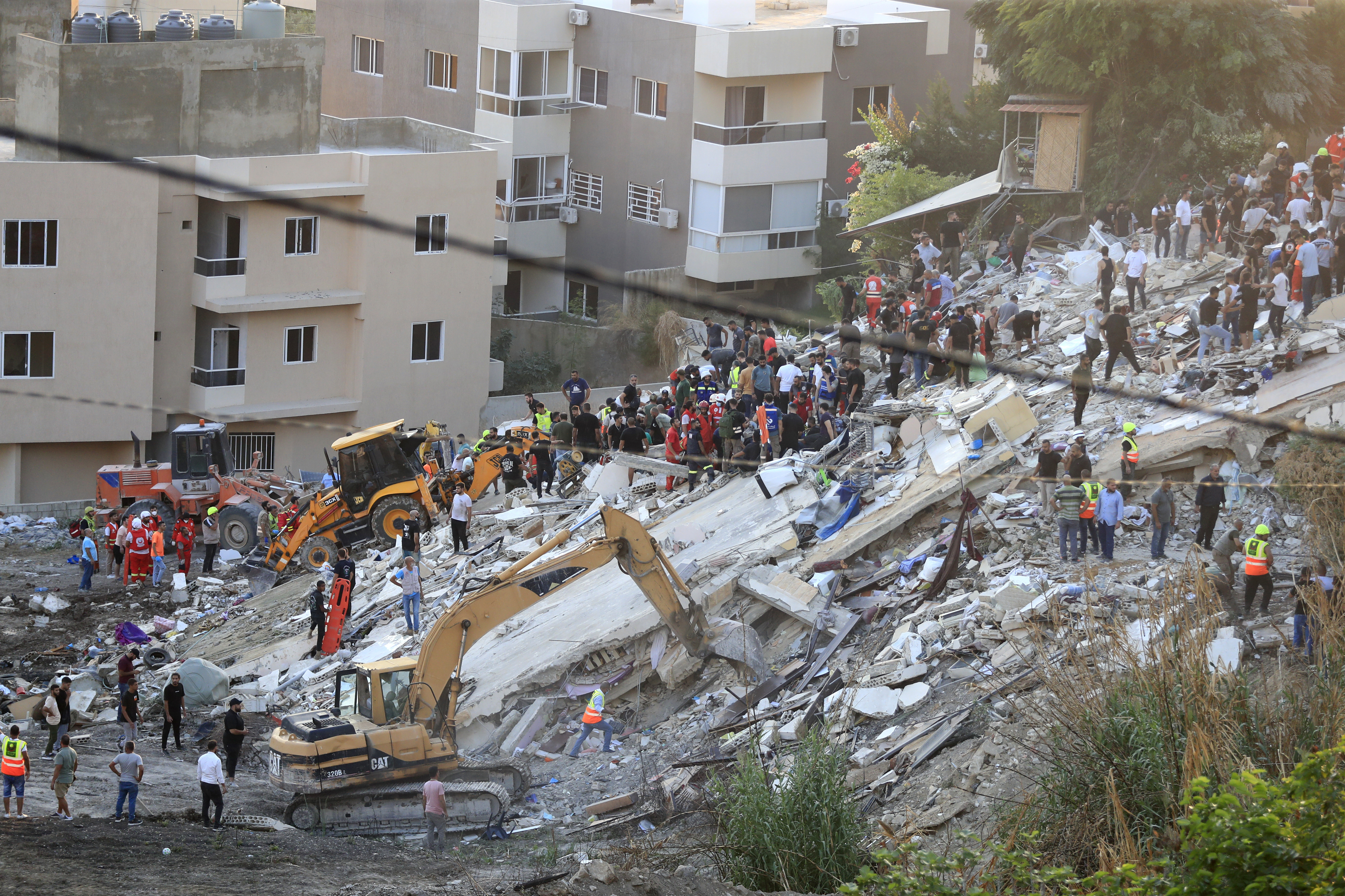 FILE - People and rescue teams search for victims after an Israeli airstrike hit two adjacent buildings, in Ain el-Delb neighbourhood east of the southern port city of Sidon, Lebanon, Sunday, Sept. 29, 2024. (AP Photo/Mohammed Zaatari, File)